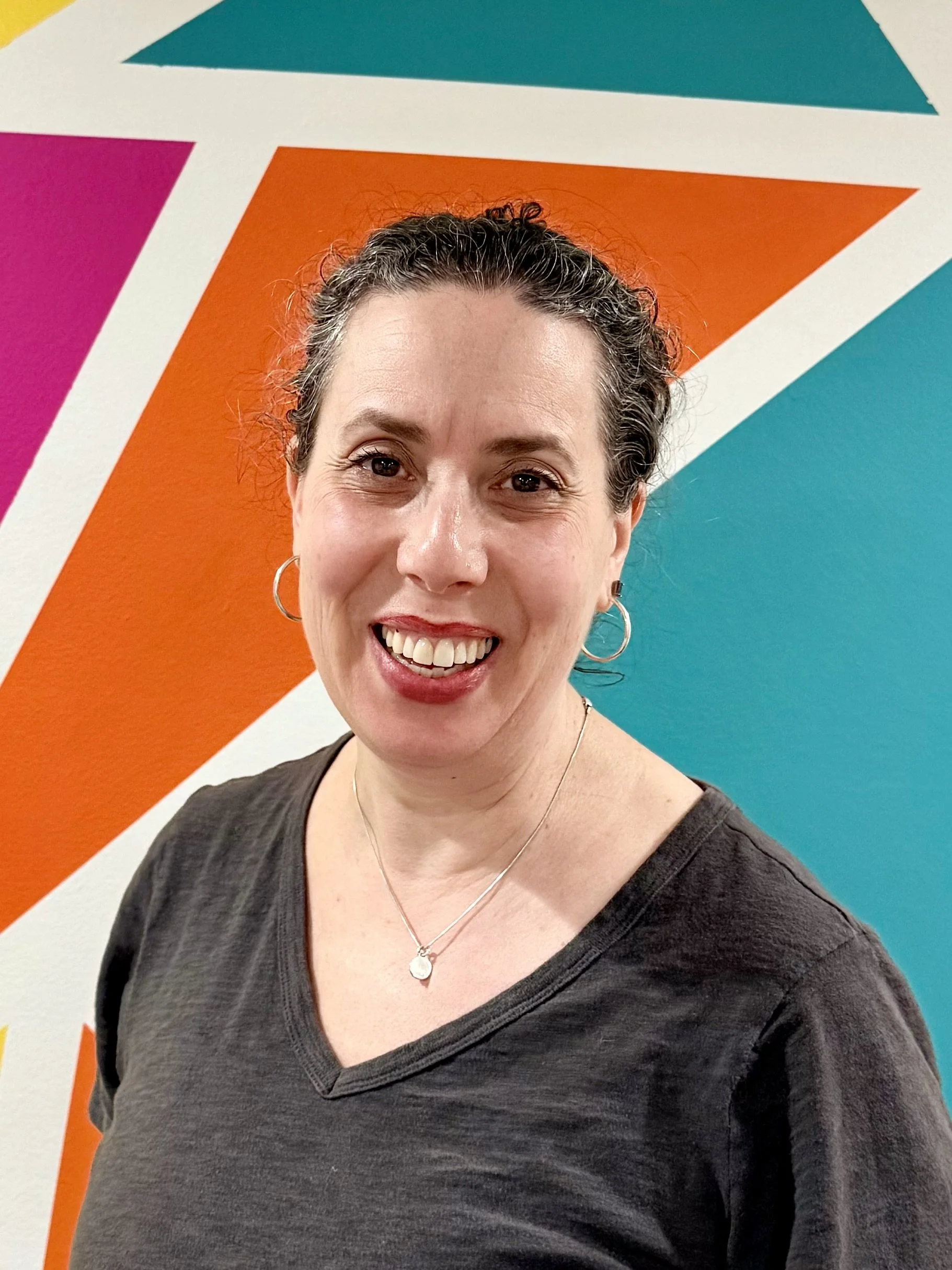 Sarah with modern, geometric mural with orange, blue and pink
