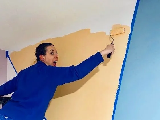 Sarah is painting a mural with yellow and blue colors.