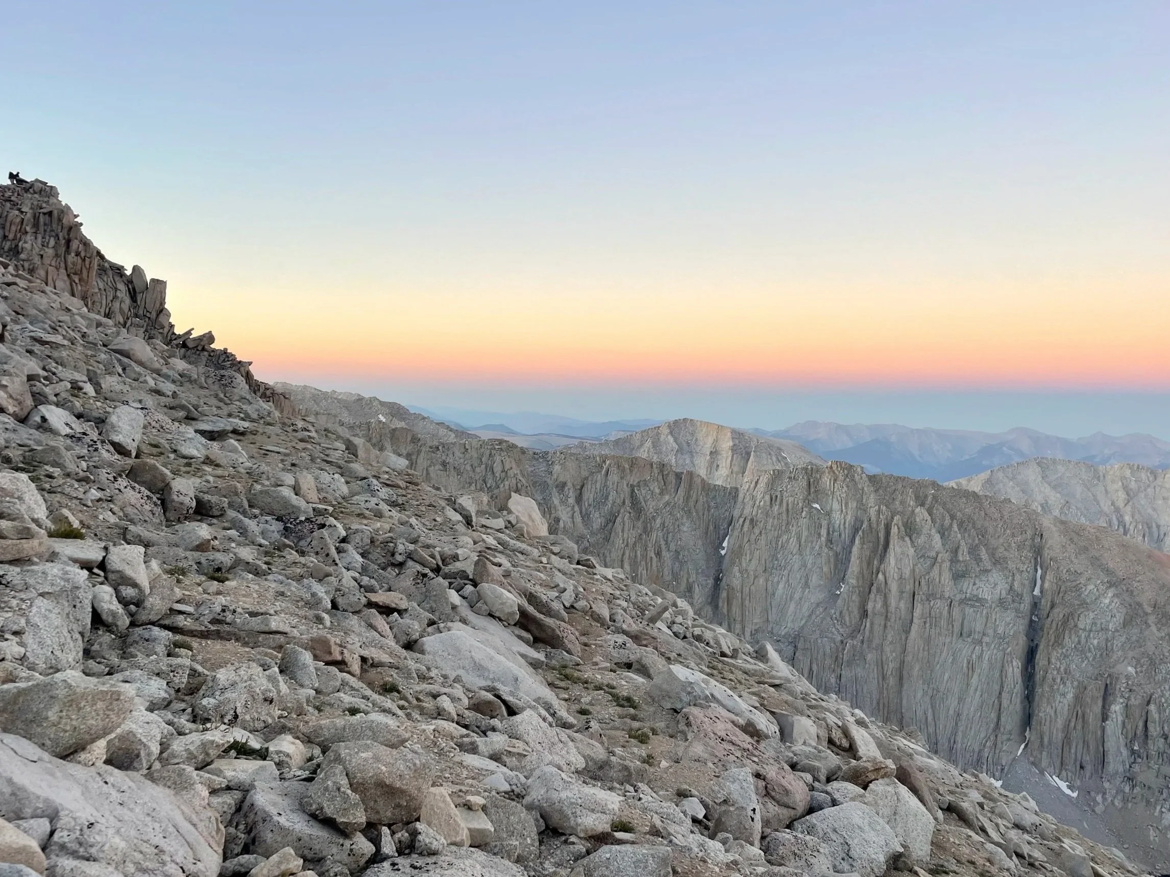 Rocky mountain terrain with rugged cliffs and a partly cloudy sky during sunset or sunrise.
