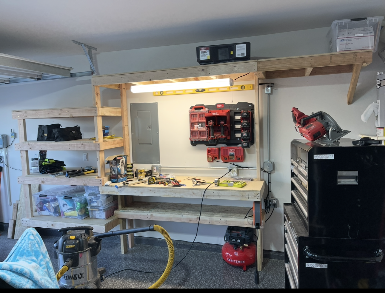 Garage workshop with a wooden workbench, power tools, tool storage, and a dust collector.