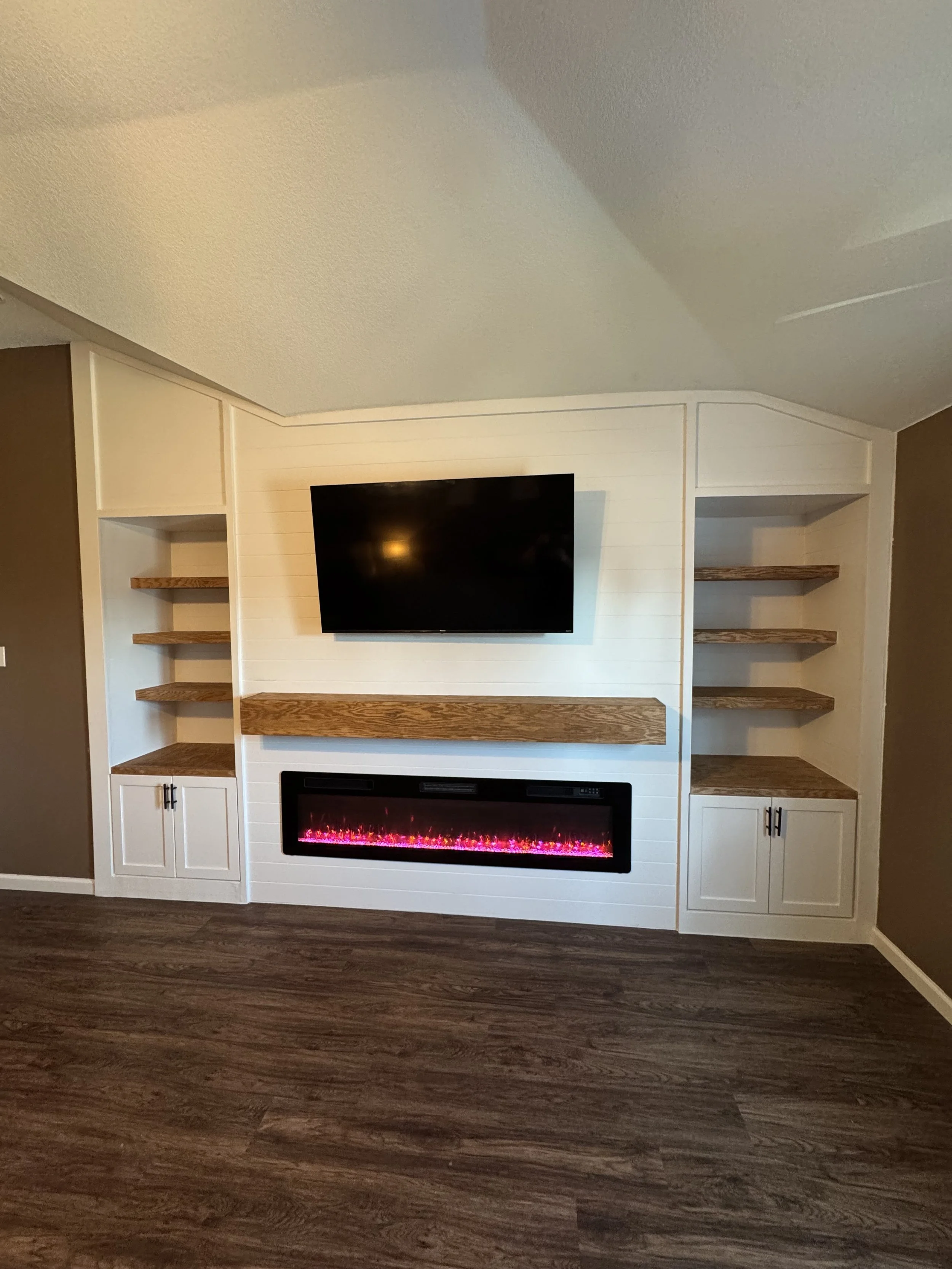 white fireplace with shiplap, bookshelf and TV.