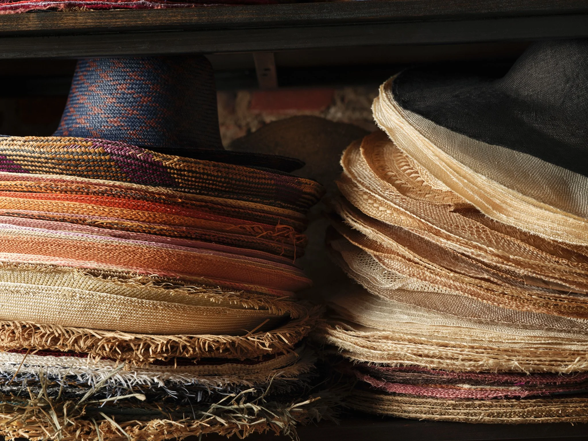 Stacks of woven straw and fabric hats arranged on shelves.