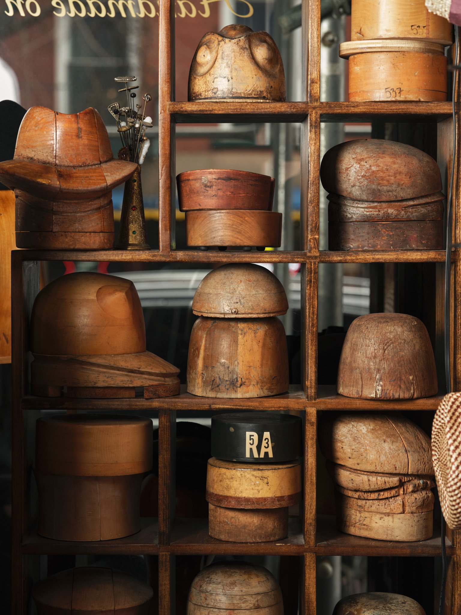 Wooden shoebox containing various wooden shoe lasts and shoe forms of different sizes and shapes on shelves.