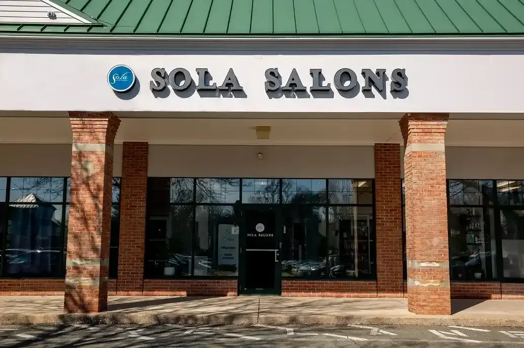 Exterior view of Sola Salons storefront with brick columns, large windows, and sign above the entrance.