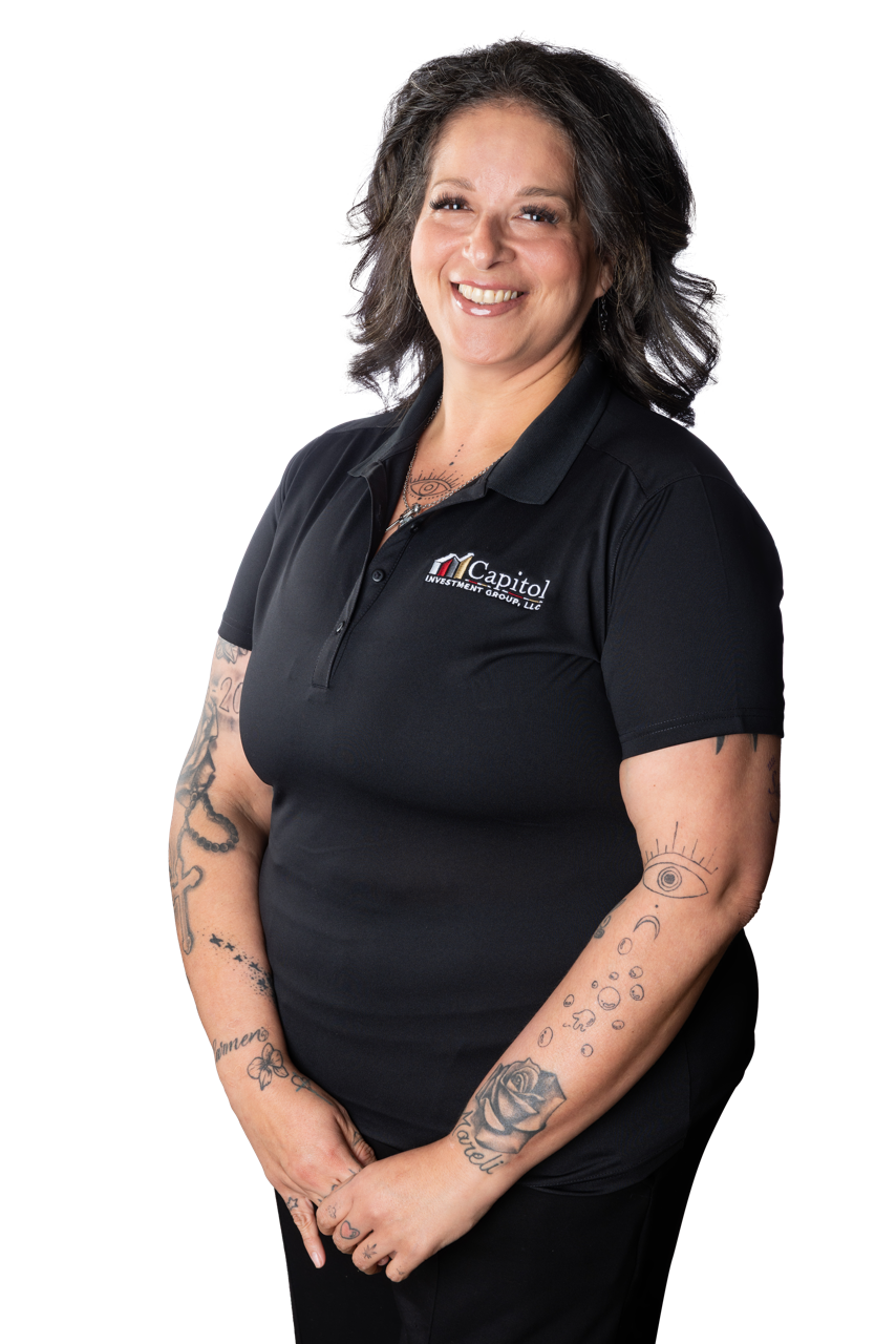 A woman with shoulder-length, wavy dark hair smiling wearing a black polo shirt with a company logo.