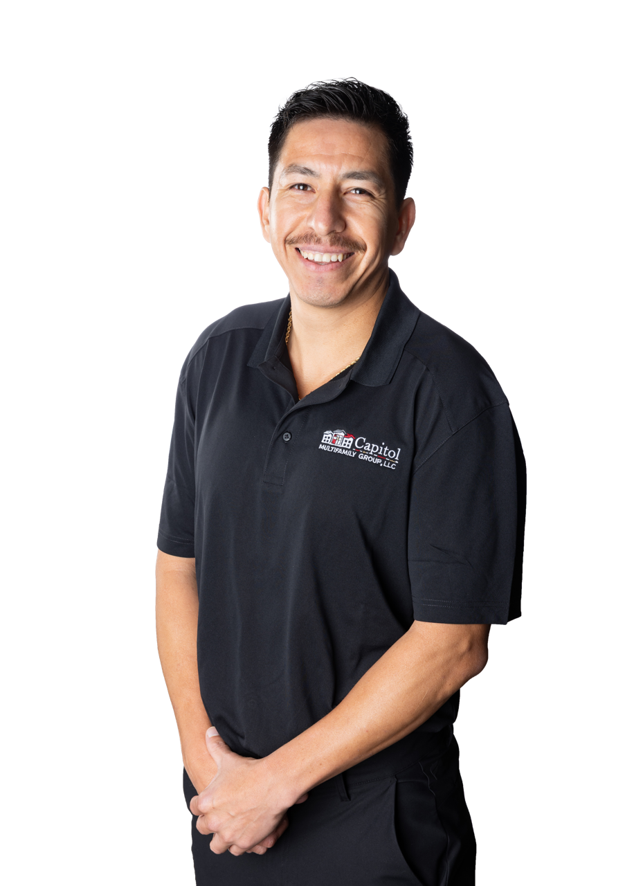 Smiling man in a black polo shirt with a company logo, standing against a plain background.