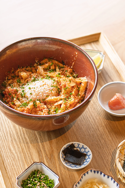 Bowl of ramen topped with grated cheese and chopped green onions on a wooden tray with small side dishes at Zaru.