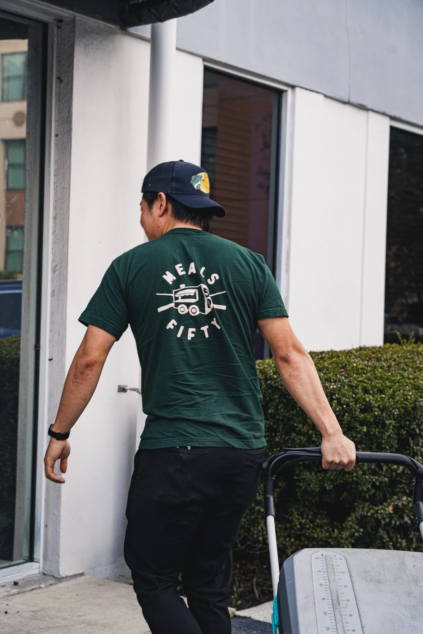 meals 50 team member wearing green shirt wheels in a cooler into a building