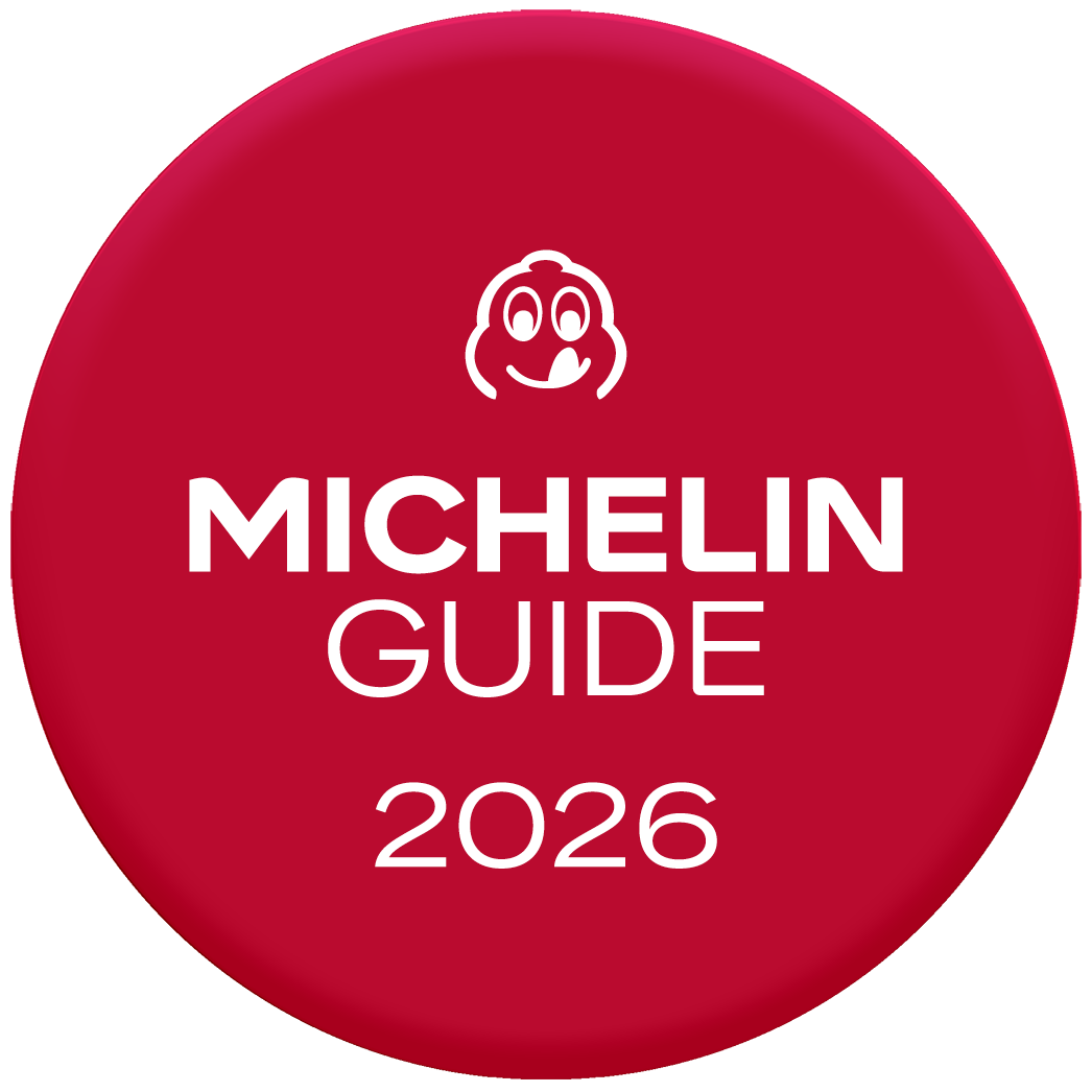 A red circular campaign sign with white text reading 'MICHELIN 2026.'
