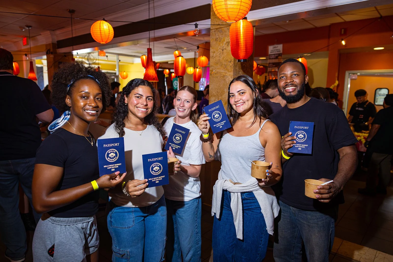 Group of people smiling and holding their passports at AAPI Night Market at Mills Market