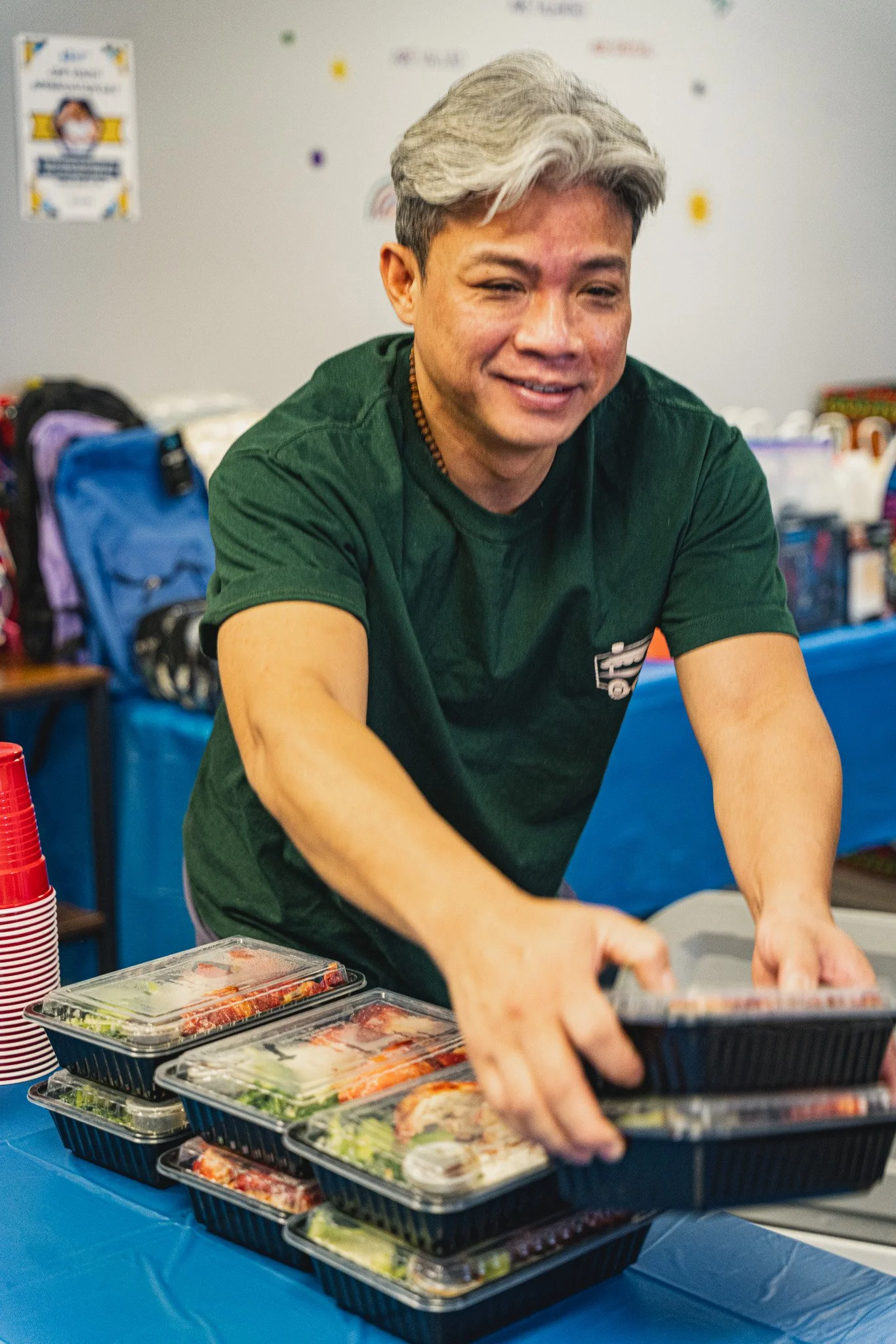 Meals 50 team member holding hot boxed meal arranges table with meals on top of table. 