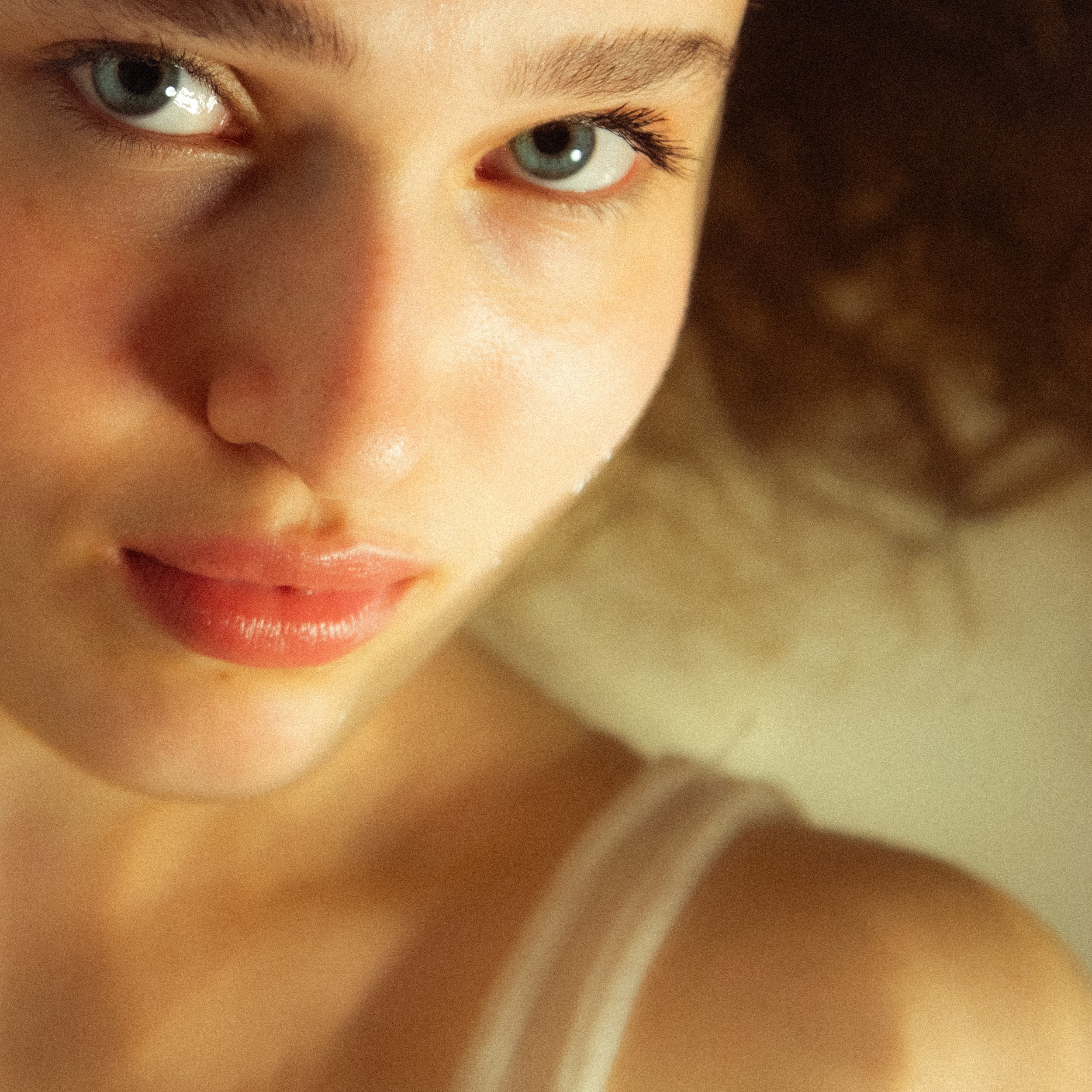 Close-up of a person's face, showing their green eyes, eyebrows, and part of their nose and lips.