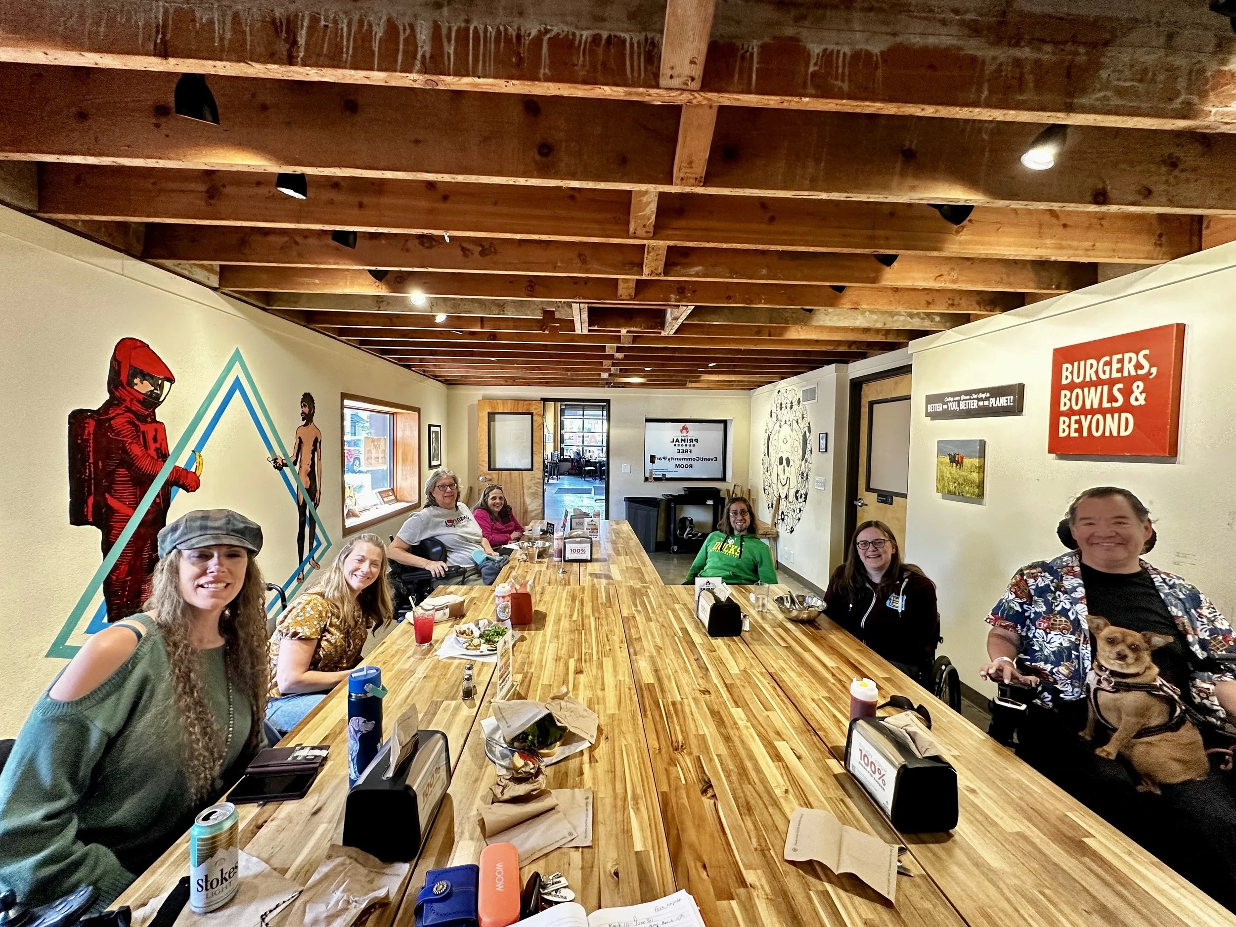 Participants at a SAND Access Together gathering share a meal and conversation at an accessible restaurant, building friendships, community, and belonging through inclusive social activities.