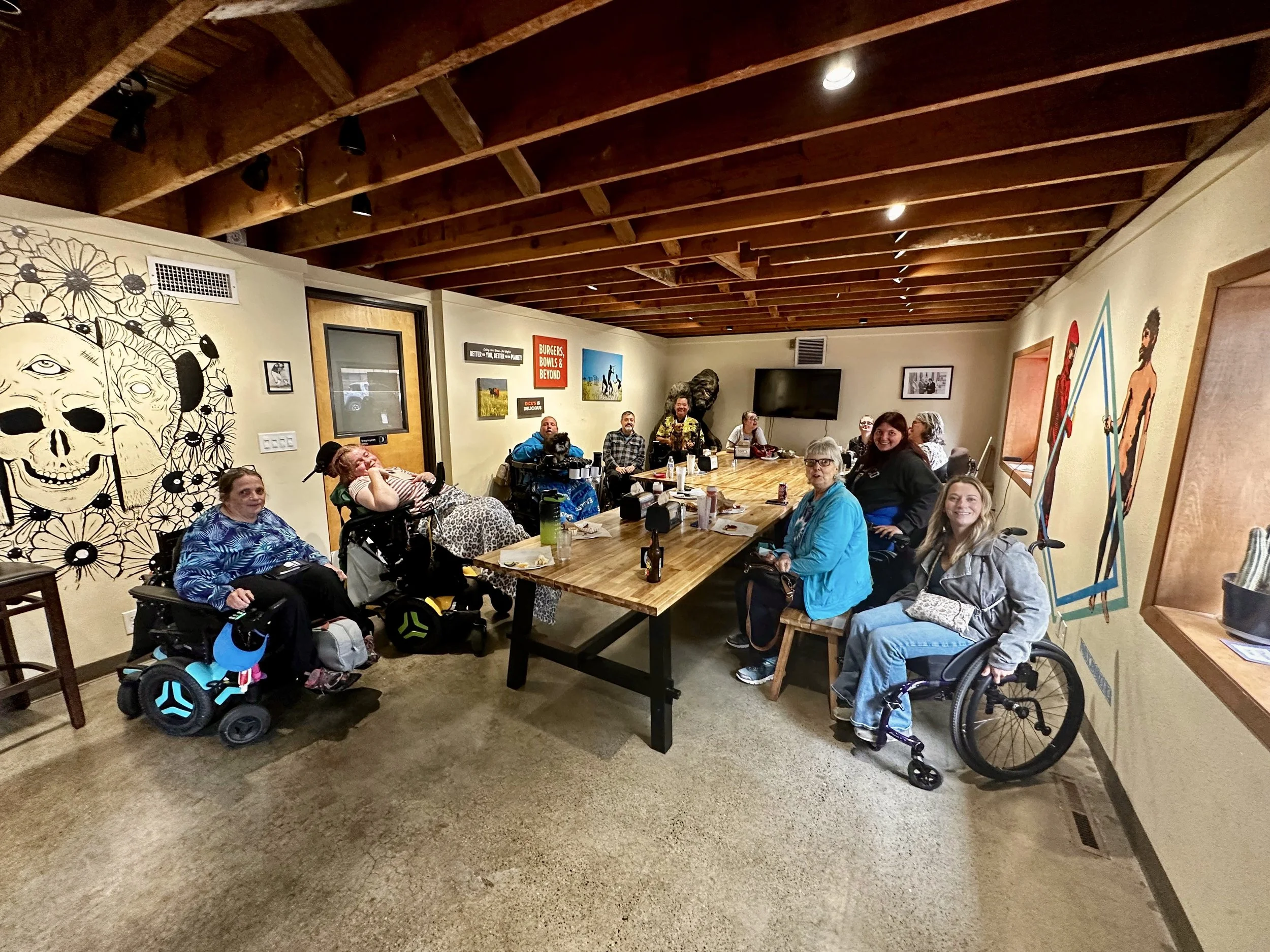 Participants at a SAND Access Together gathering share a meal and conversation at an accessible restaurant, building friendships, community, and belonging through inclusive social activities.