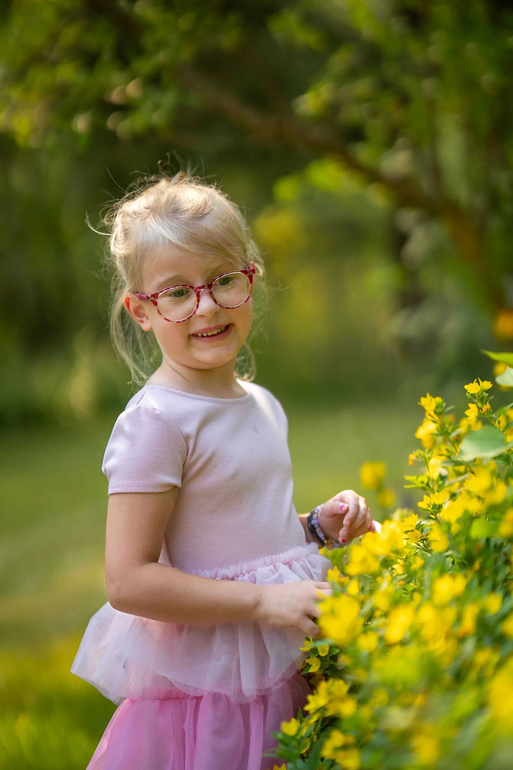 A child smelling and playing with flowers getting pictures wth flowers