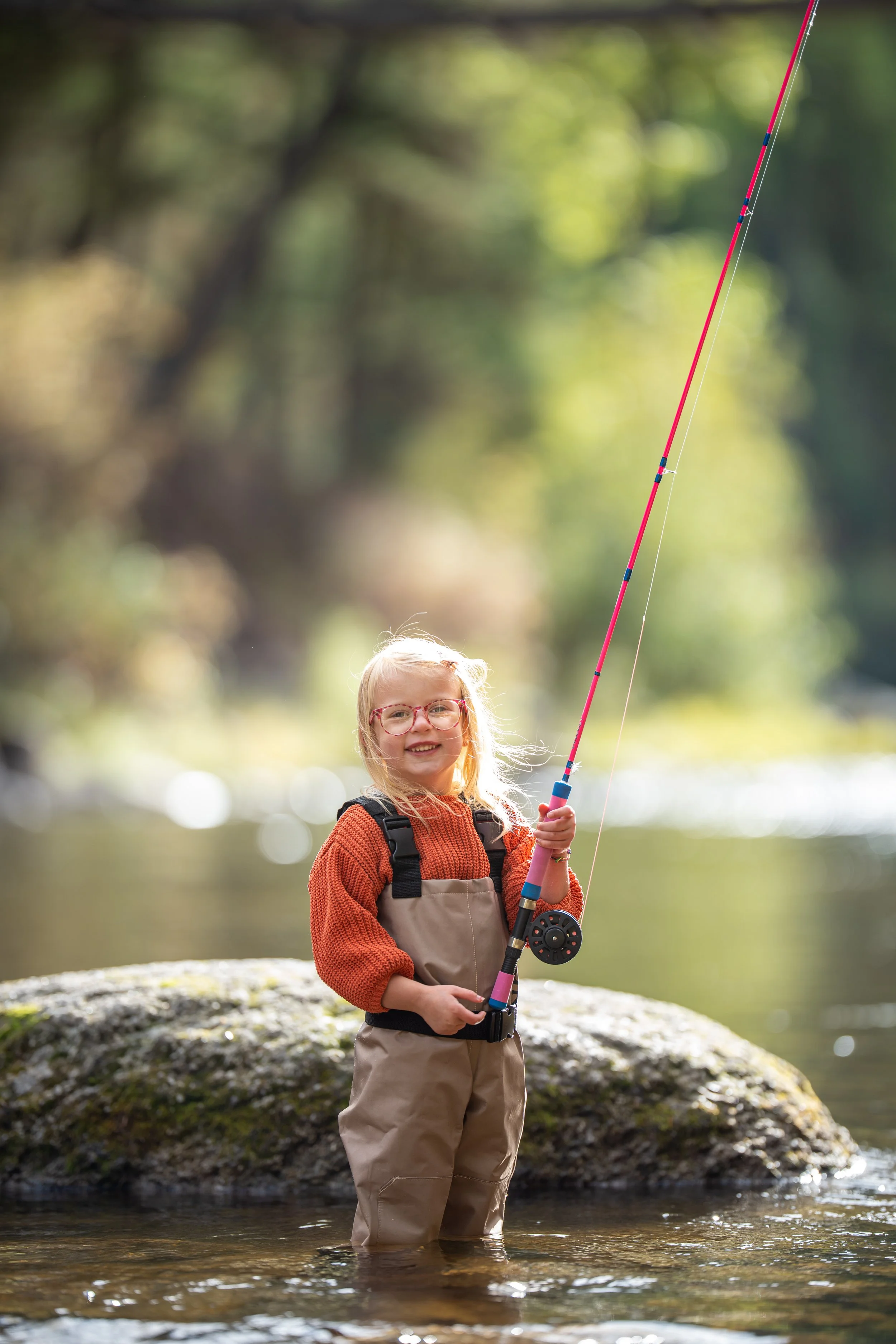 Kid in waders in the river in Montana