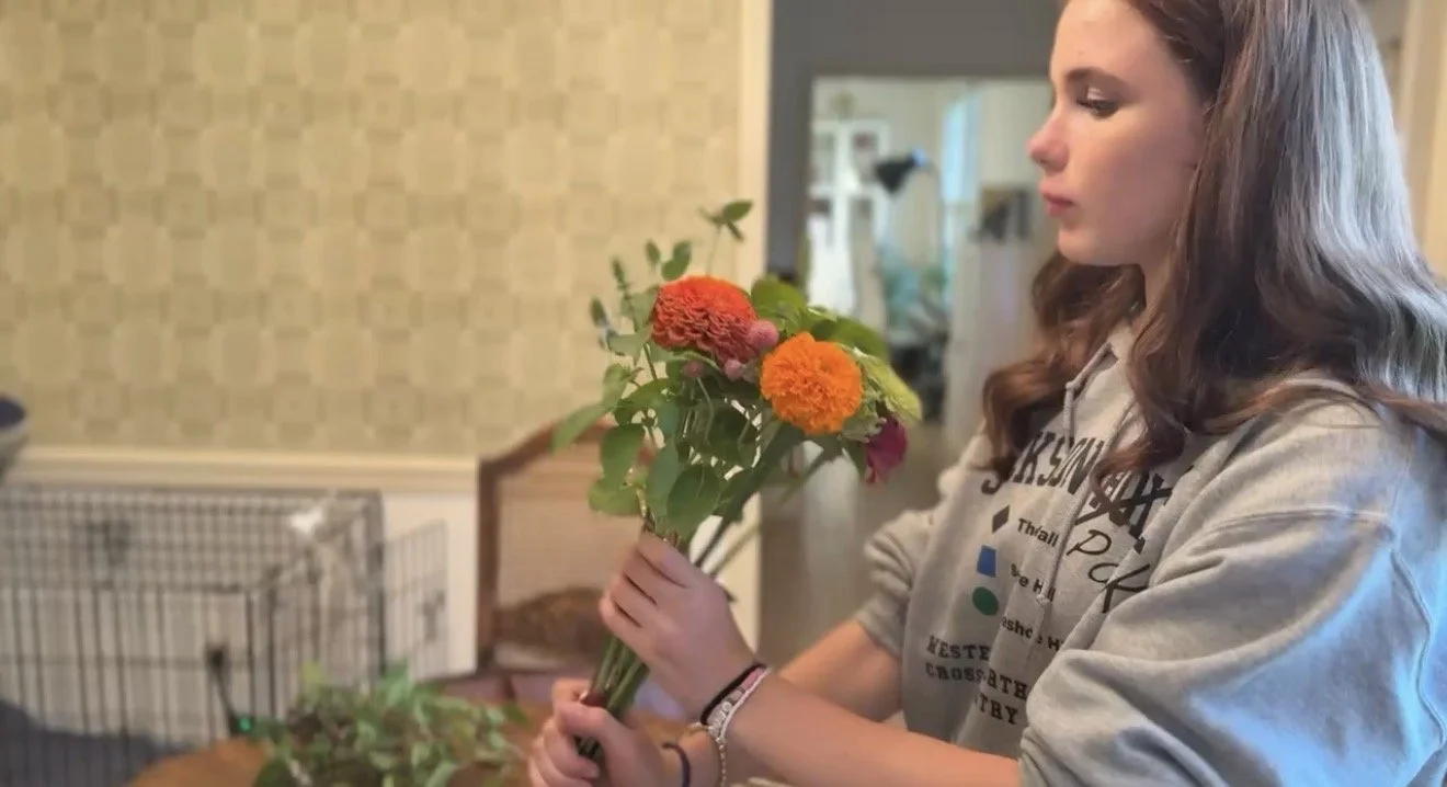 Young woman holding a bouquet of colorful flowers indoors.
