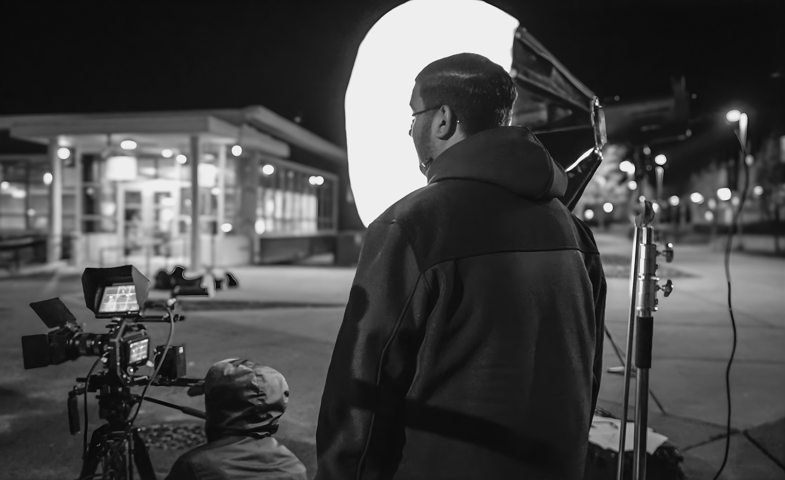 Professional cinematographer operating camera during nighttime film production for ARC Lens Productions as Gurdil Dardi oversees production.