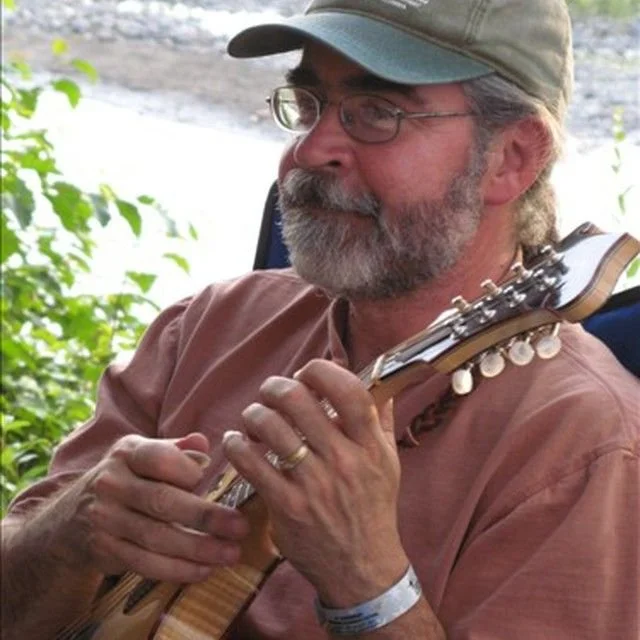 Man sitting and playing a mandolin.