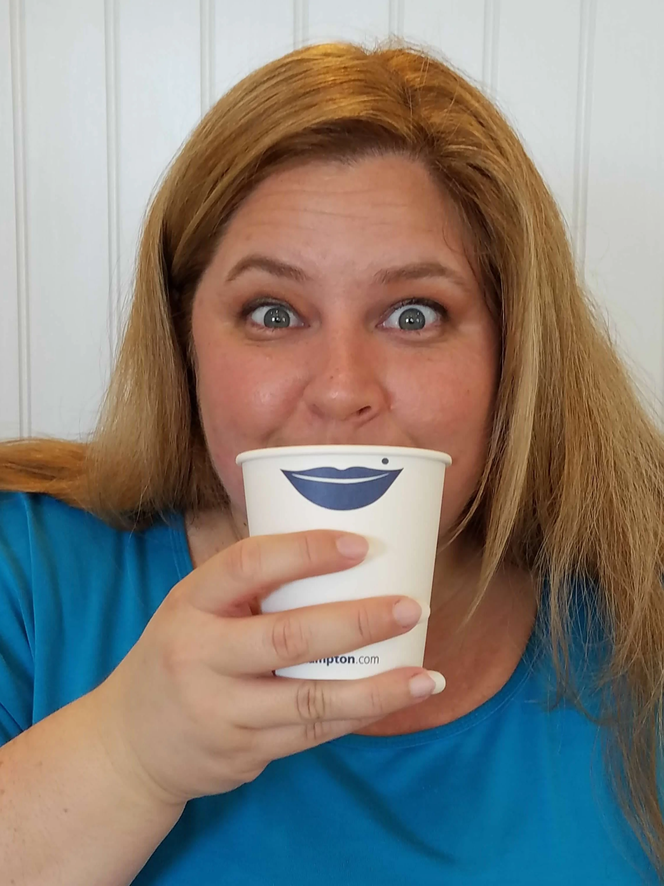 Silly image of woman holding a cup up to her face. That cup has drawn lips and are held where her lips should be located.