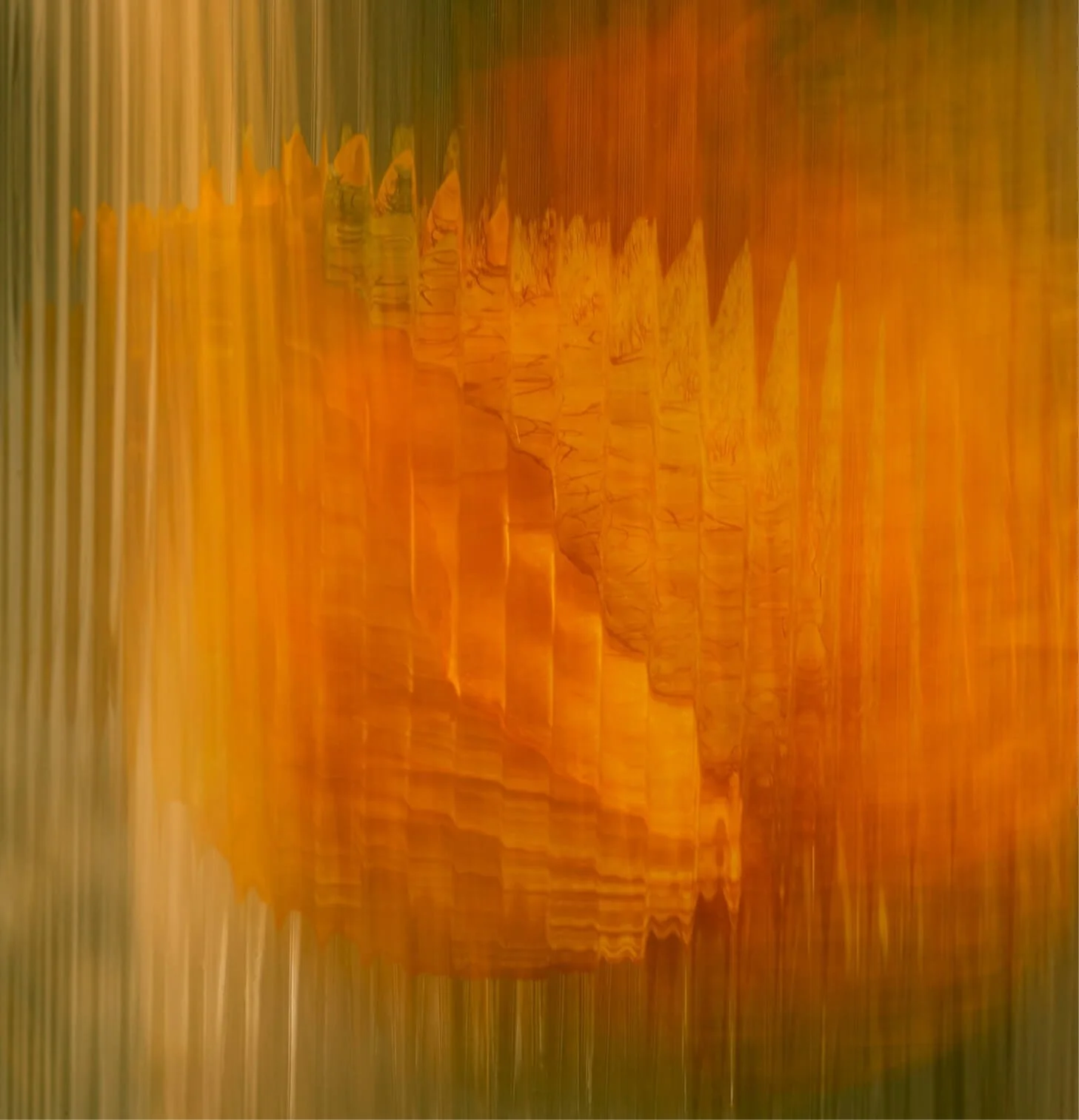 A blurry photograph of a sunset over a body of water with mountains in the background. The image has a distorted, vertical streaking effect.