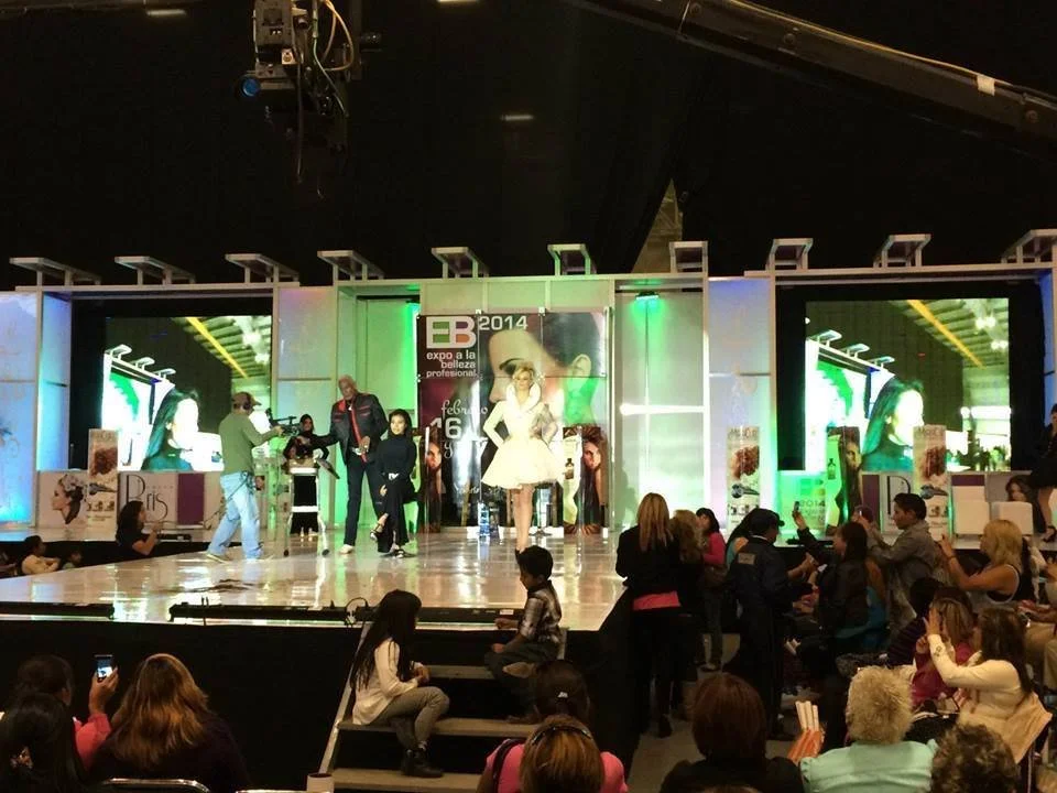 Personas en un escenario de show, algunos toma fotos, otros están en el público observando.