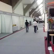 Pasillo amplio en una oficina o centro comercial, con dos personas caminando y un carrito de compras.