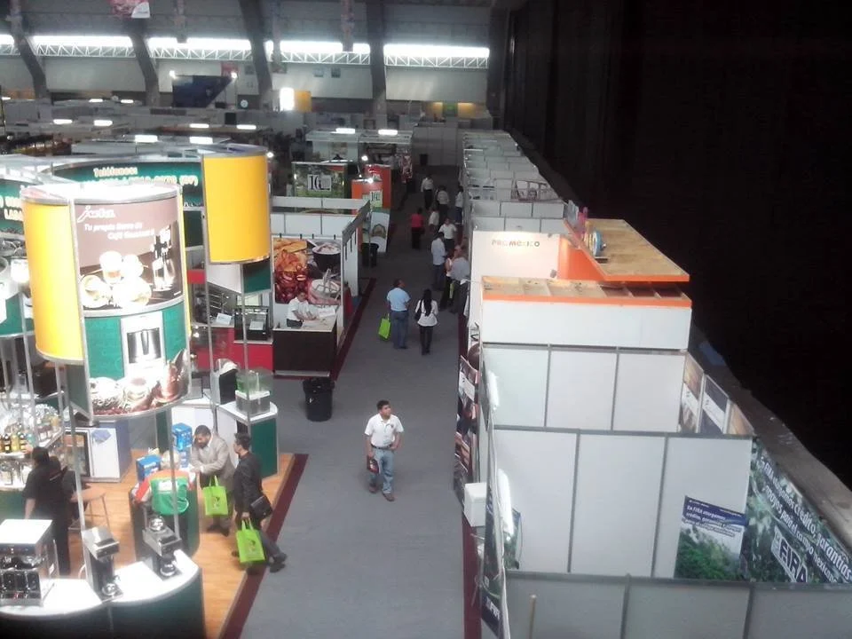 Vista aérea de una feria o exposición con varios stands y personas caminando entre ellos.