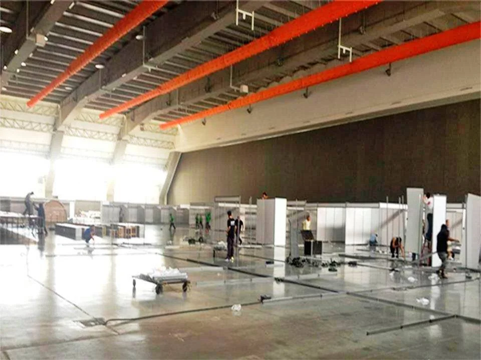 Personas armando cabinas en un espacio amplio, posiblemente en un evento o feria.