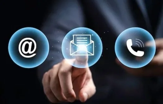 Ícono de correo electrónico, ícono de mensaje y ícono de teléfono flote sobre un fondo oscuro, con una mano tocando la pantalla.