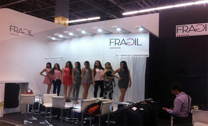 Seis modelos femeninas posando frente a un fondo blanco con el logotipo 'FRADIL', en una especie de pasarela o exhibición de moda, en un evento o salón de exposición.