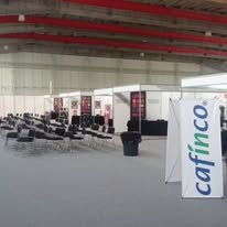 Área de espera en una estación de autobuses con sillas y una señal de Caficco en español.