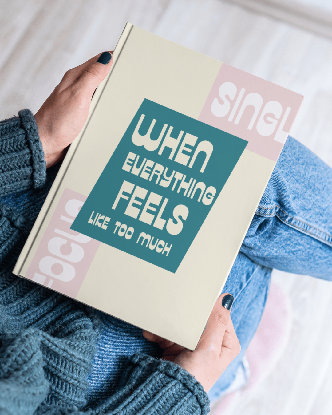 Person in a blue sweater and jeans holding a book with the quote "When everything feels like too much" on the cover.