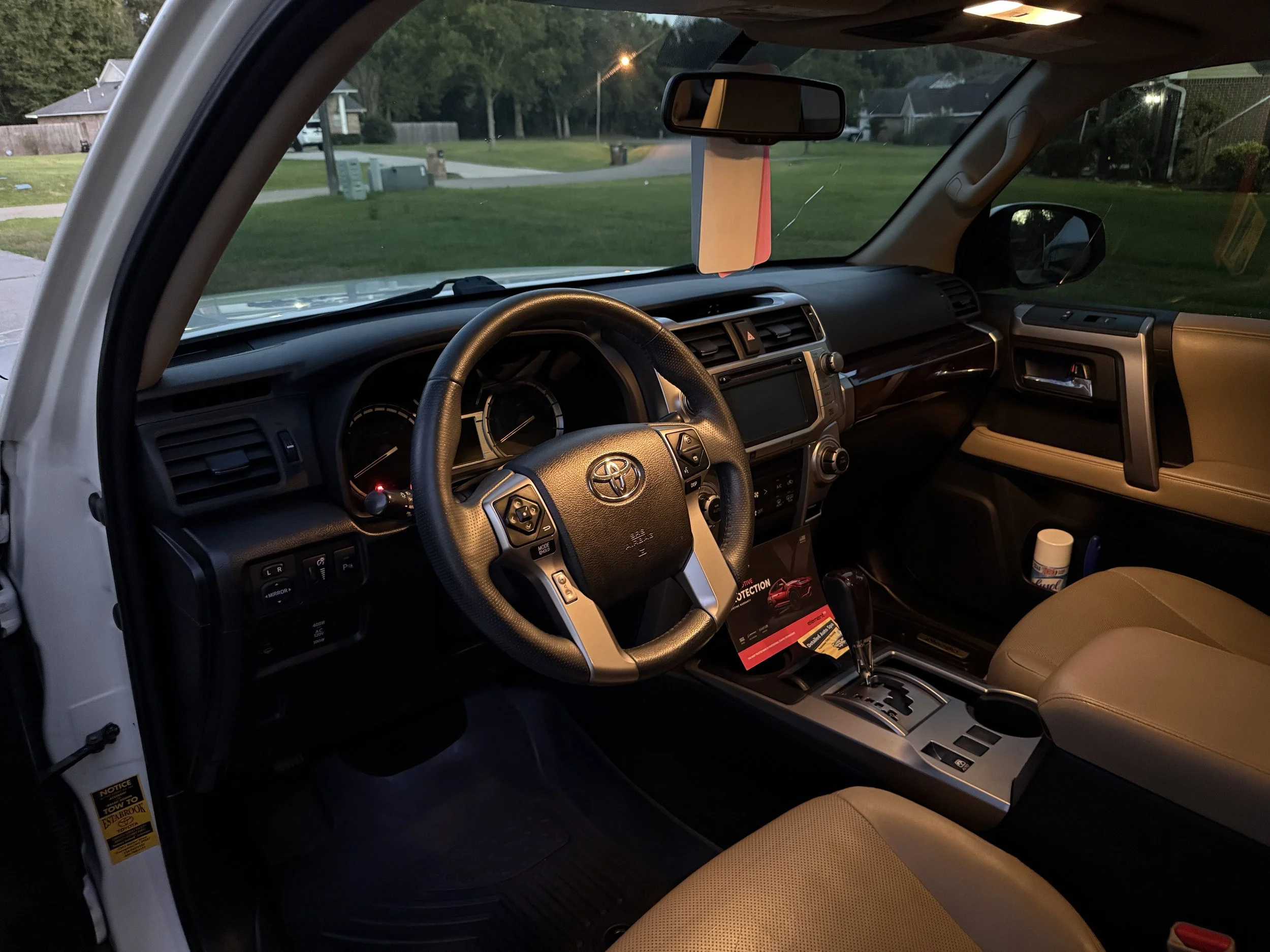 Interior view of a Toyota vehicle, showing the dashboard, steering wheel, gear shift, and front seats during dusk.