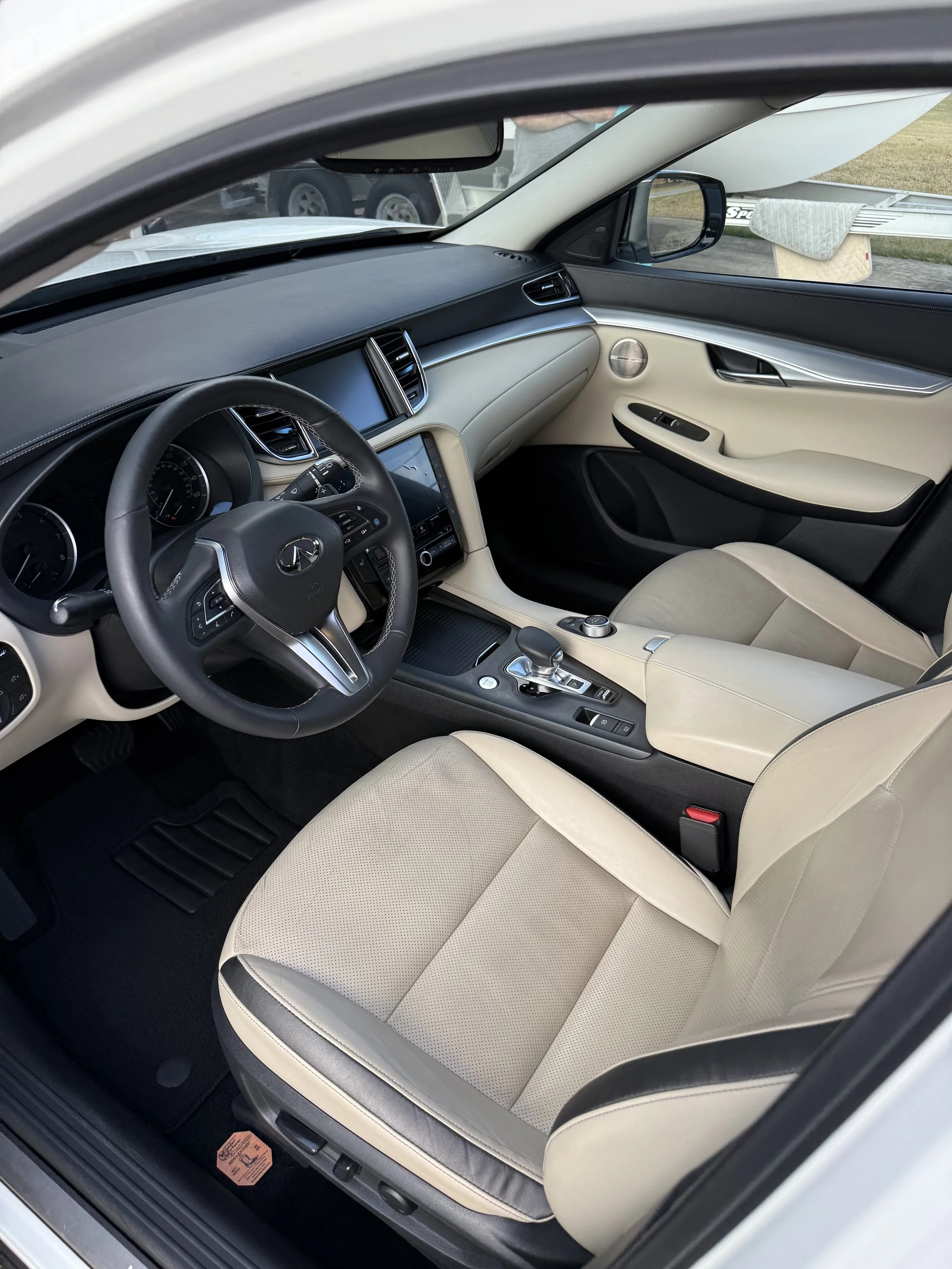 Interior of a luxury car with a black leather dashboard, beige leather seats, and modern controls.