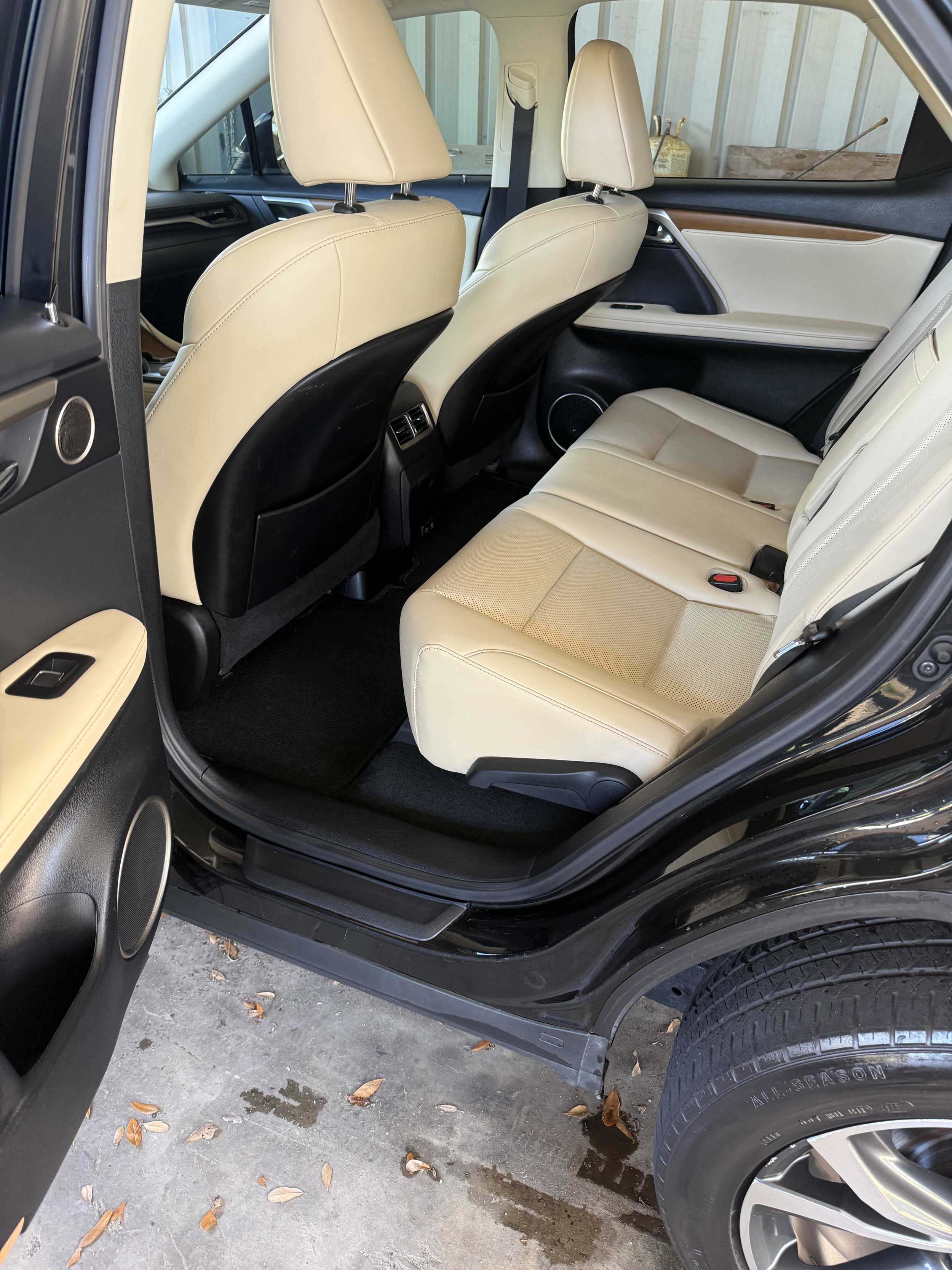 The interior of a black SUV with beige leather seats, showing the rear seats, front seats, and part of the door panel.