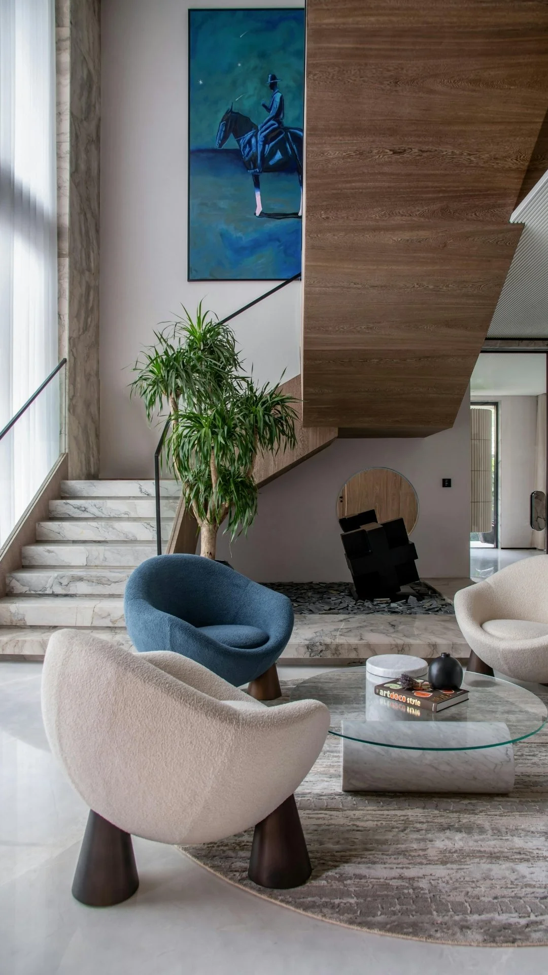 Moderner Wohnbereich mit Design-Sesseln, Marmortisch und Marmortreppe