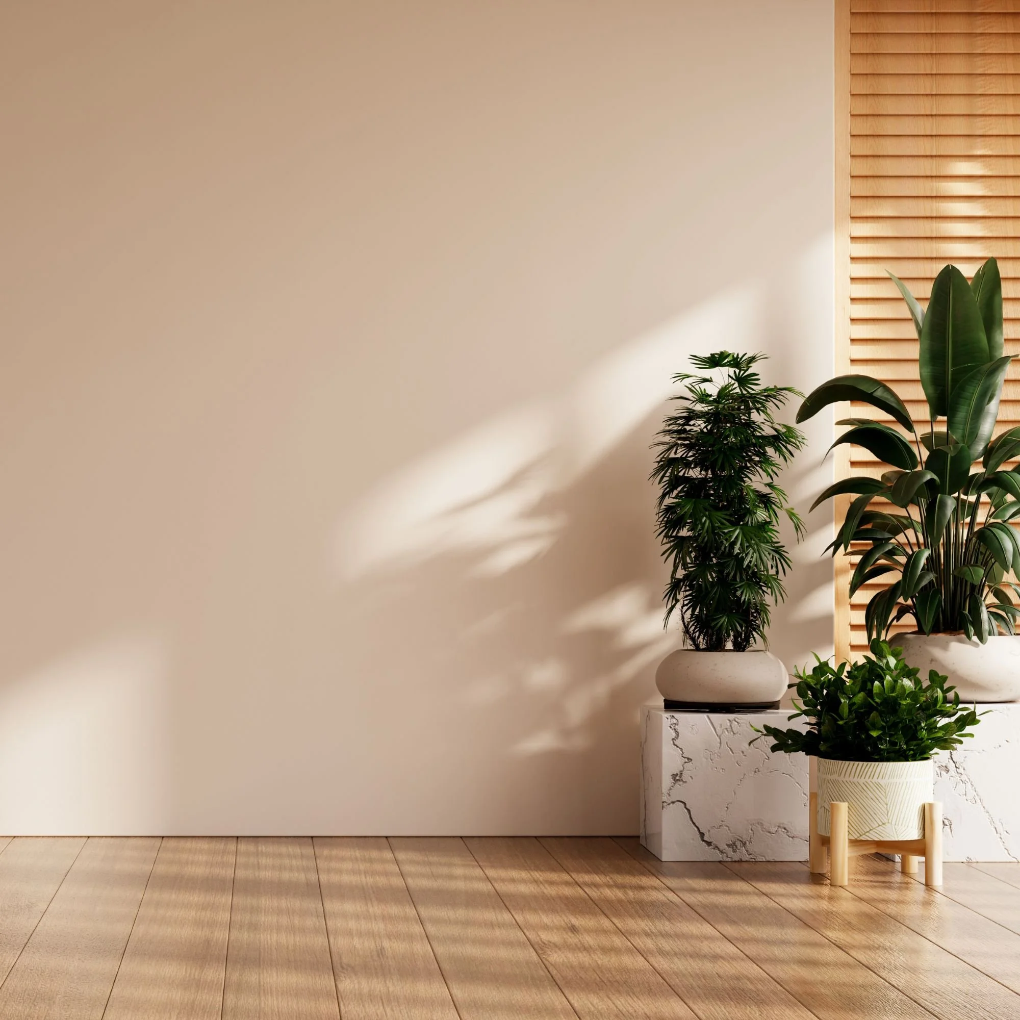 Interior of a modern room with wooden flooring, a beige wall, and indoor plants near a wooden slat wall, decorated with a white marble and black veined side table.