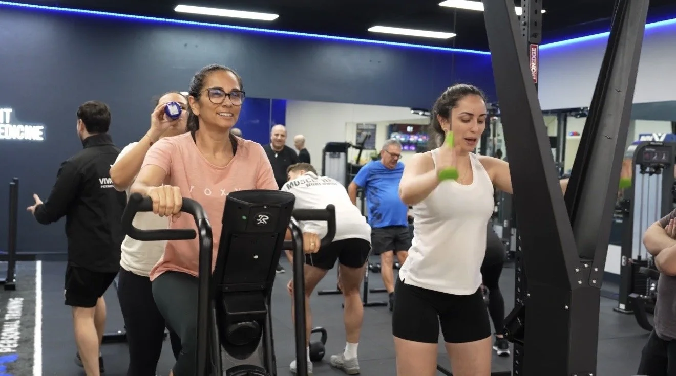 Female clients training on the assault bike and ski-erg machine during a small group session at Viva Active Burwood