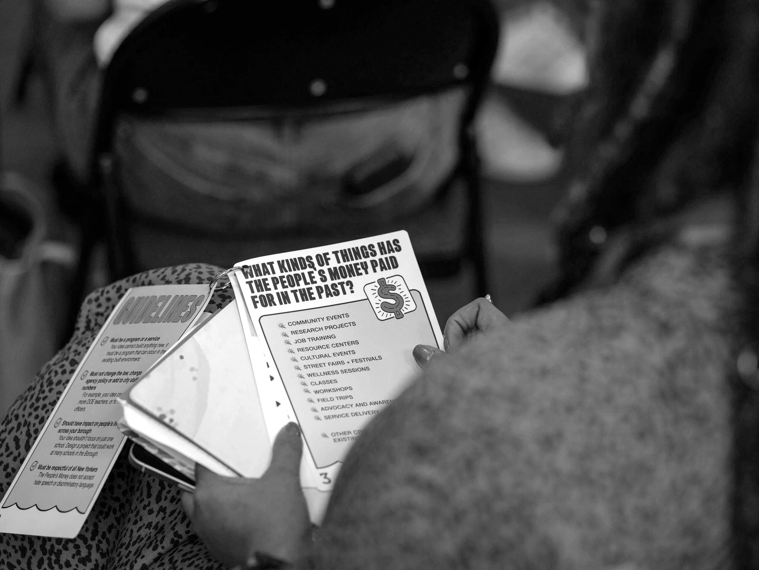 A person holding a flyer that lists community events, research projects, job training, and other activities.