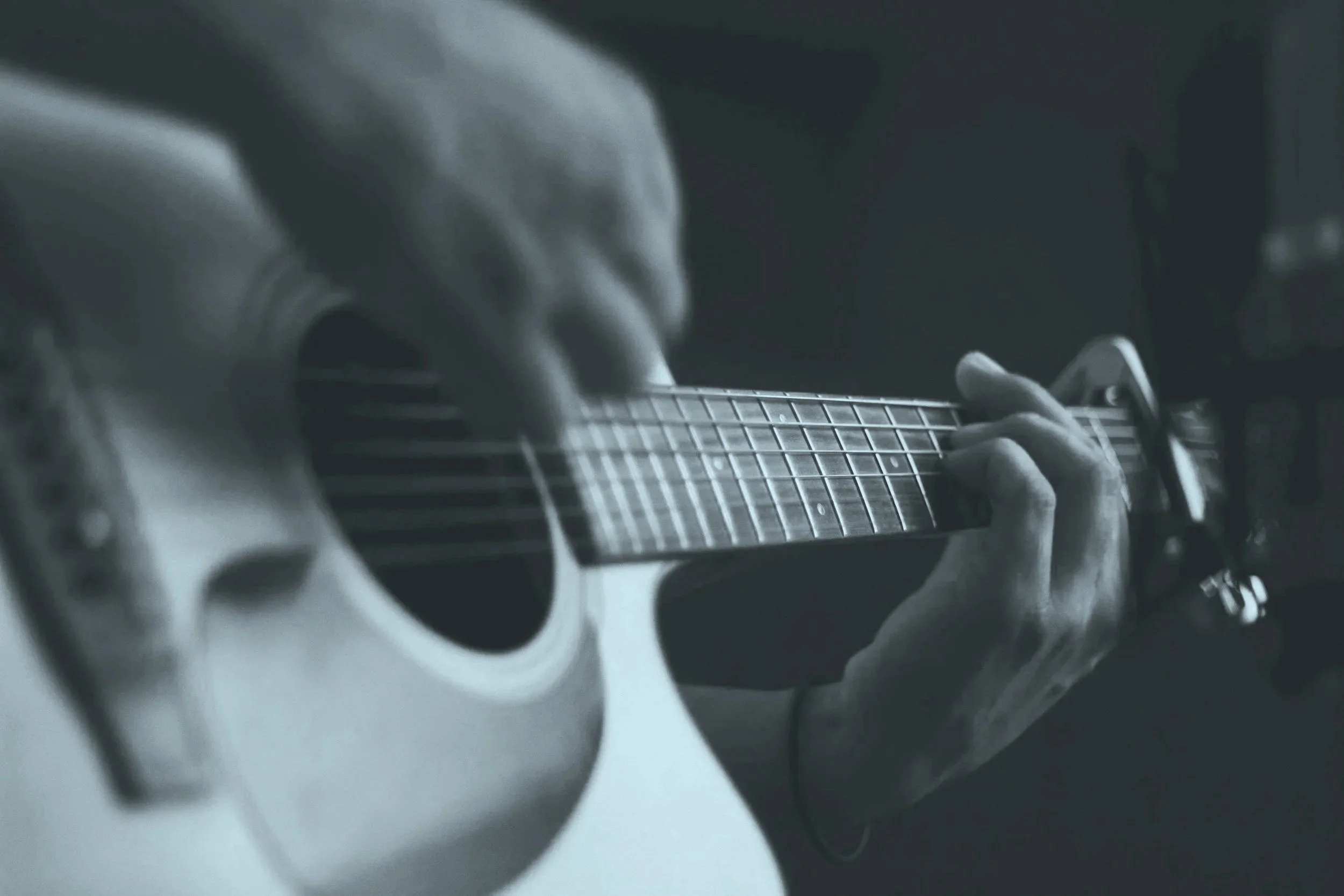 Close-up of a person playing an acoustic guitar, black and white photograph.