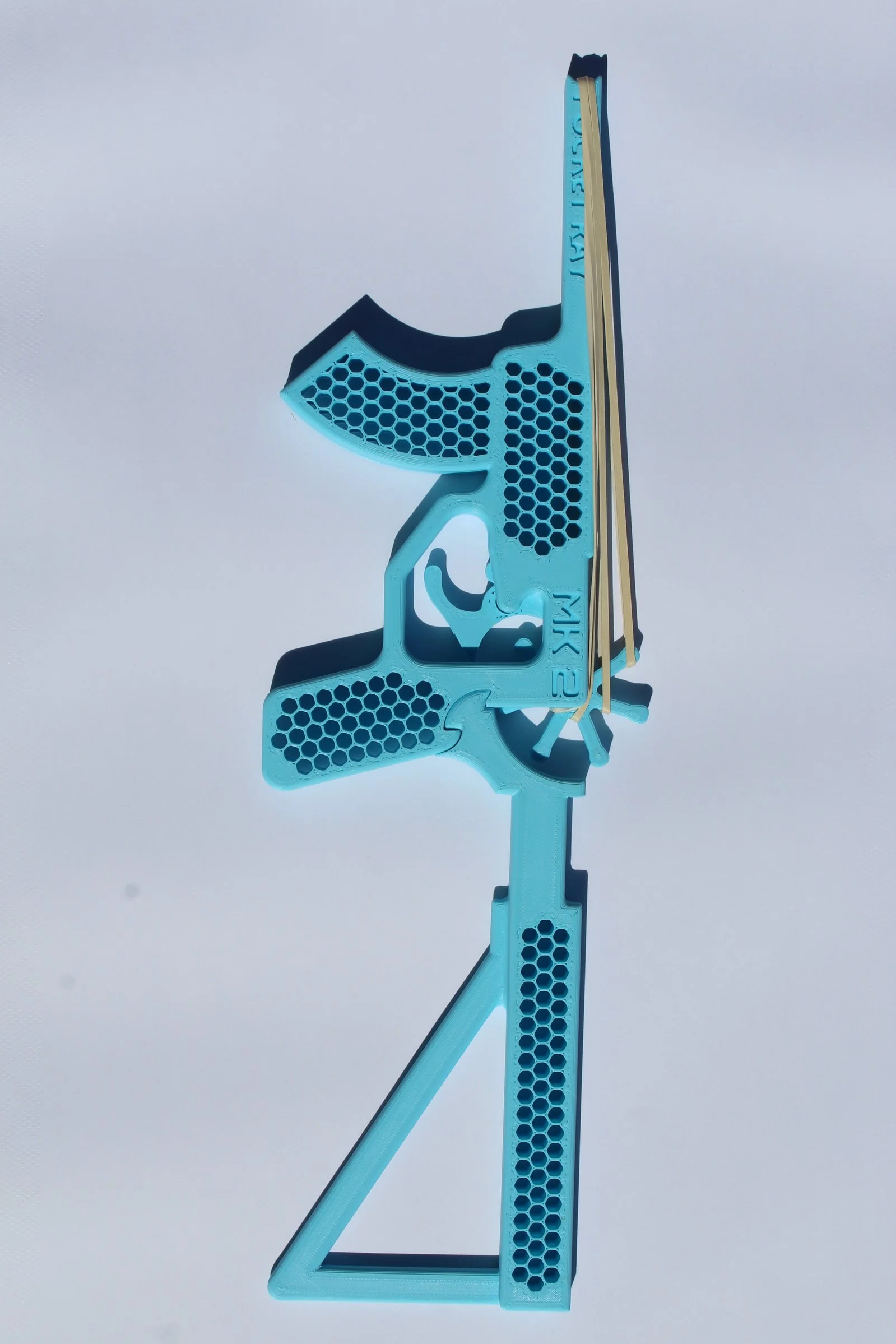 A blue and yellow plastic toy shaped like a handgun with a gun-shaped outline and honeycomb design on the grip, set against a light background.