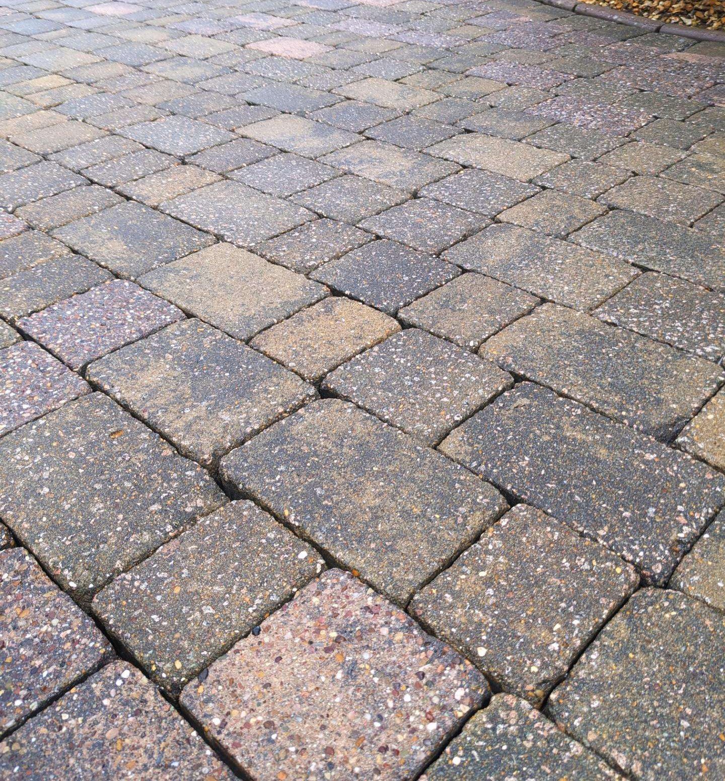 Close-up view of a paved stone walkway made of rectangular stones with speckled surfaces, arranged in a staggered pattern.
