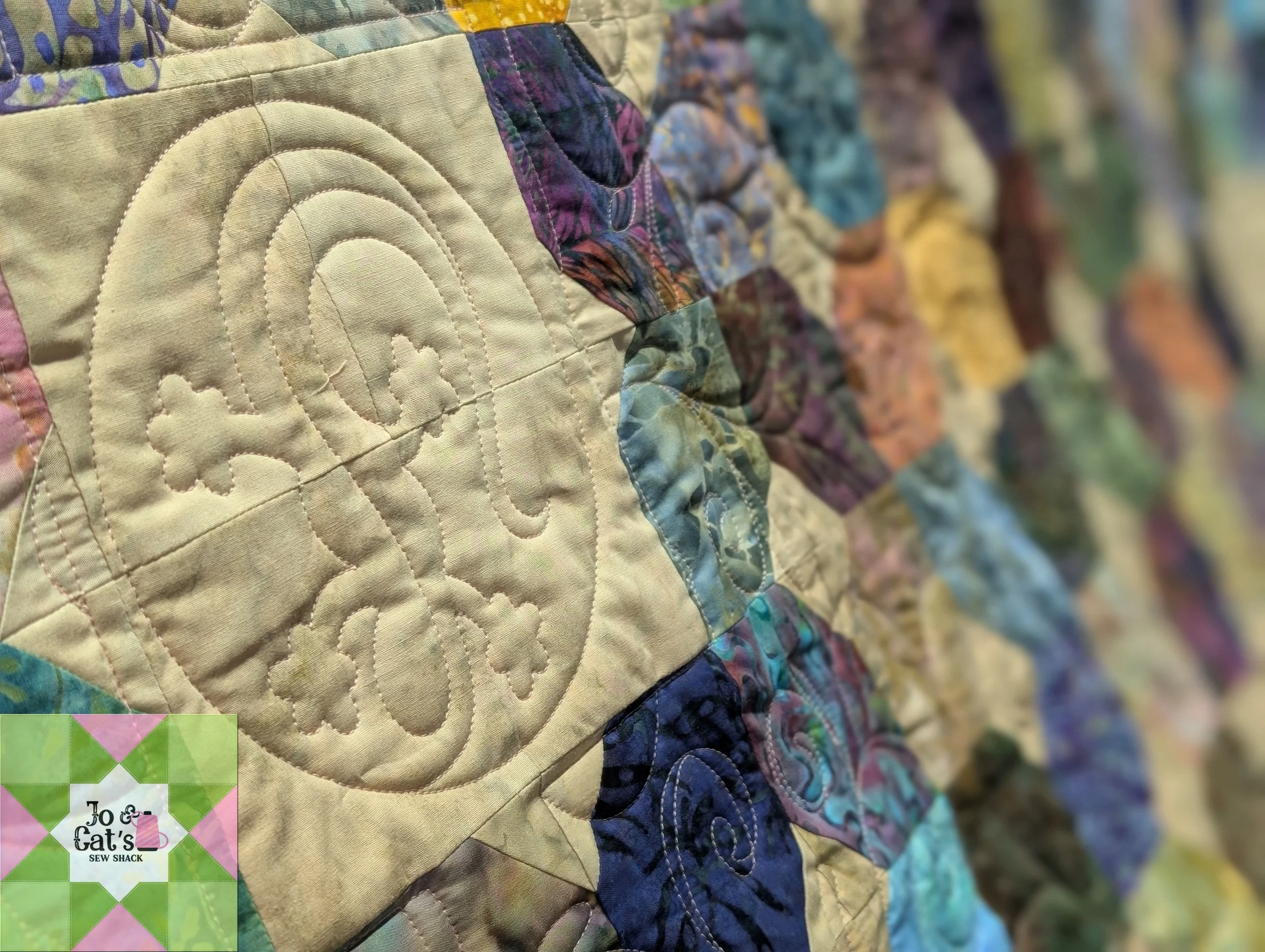 Close-up view of a colorful quilt with intricate stitching patterns and various fabric patches in multiple colors and patterns.