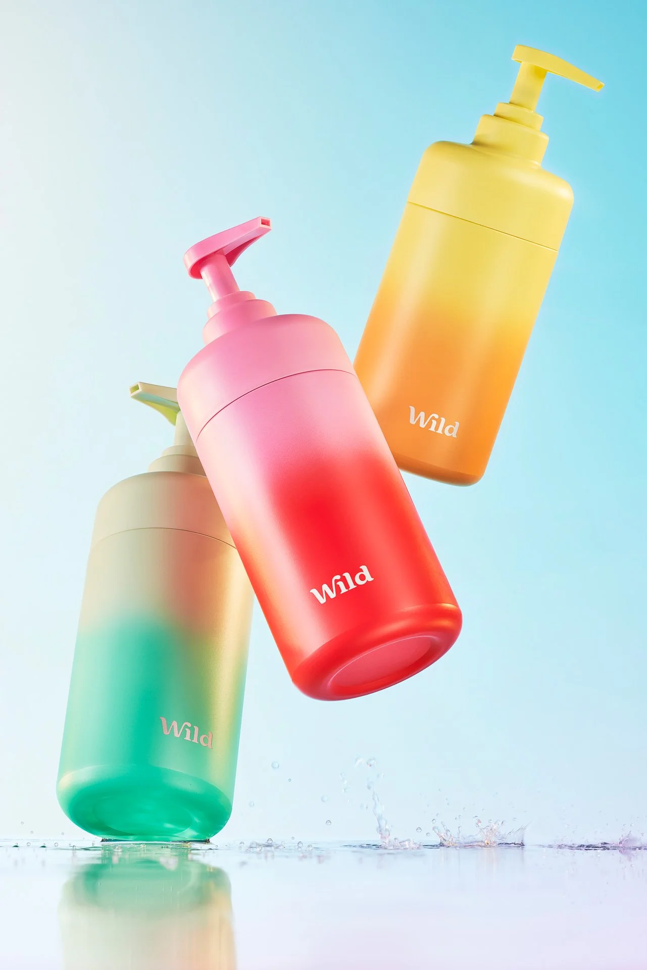 Three ombre bottles, flying in the air, bouncing off the body of water.