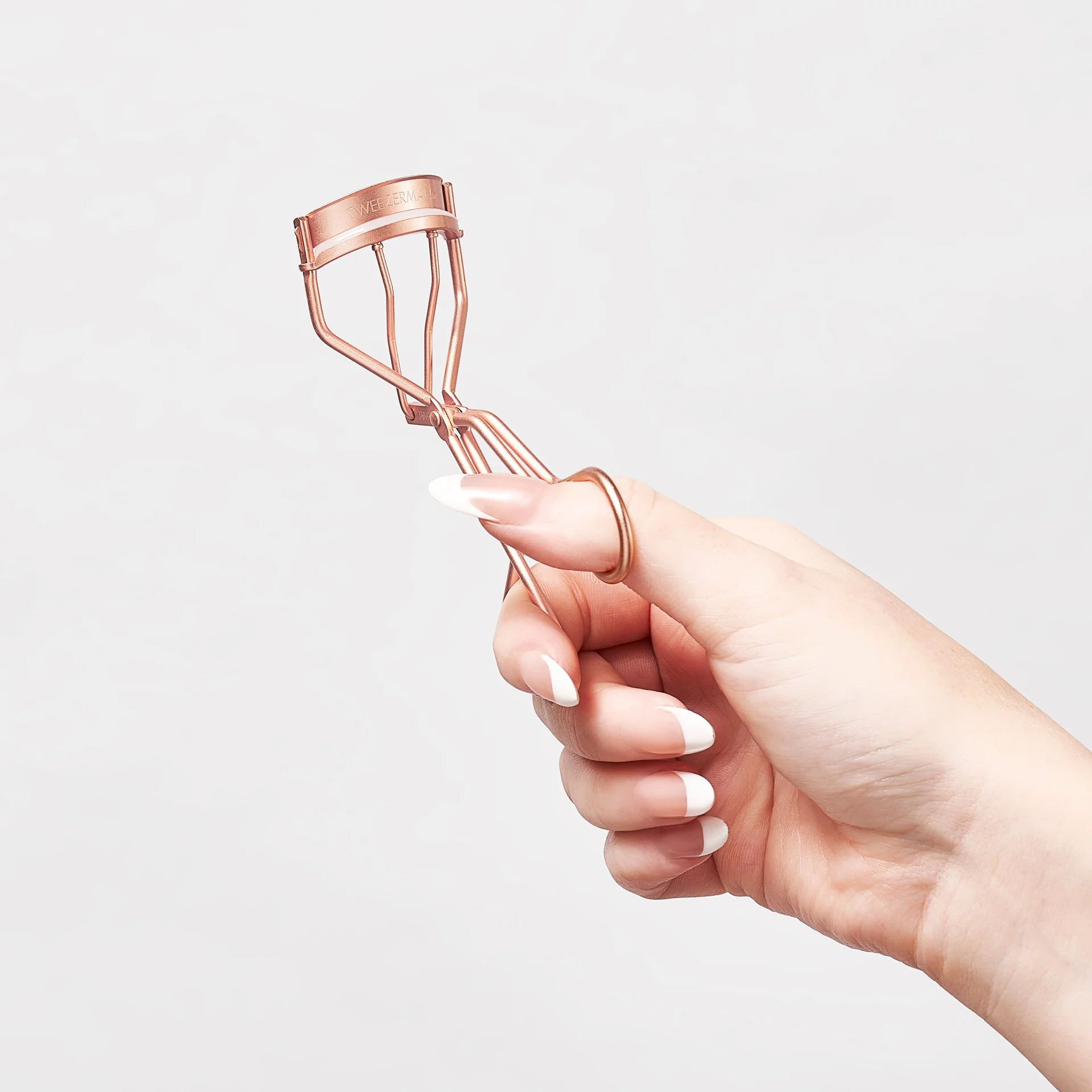 Hand holding a rose gold eye lash curler.