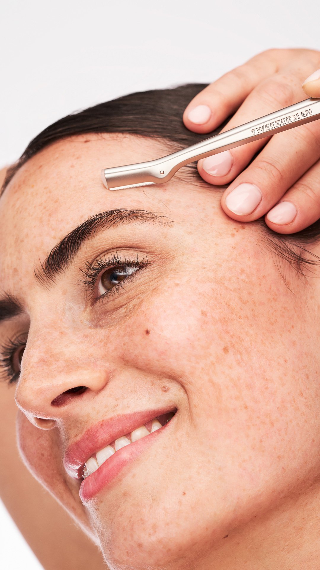 Smiling white model using a facial razor on her face