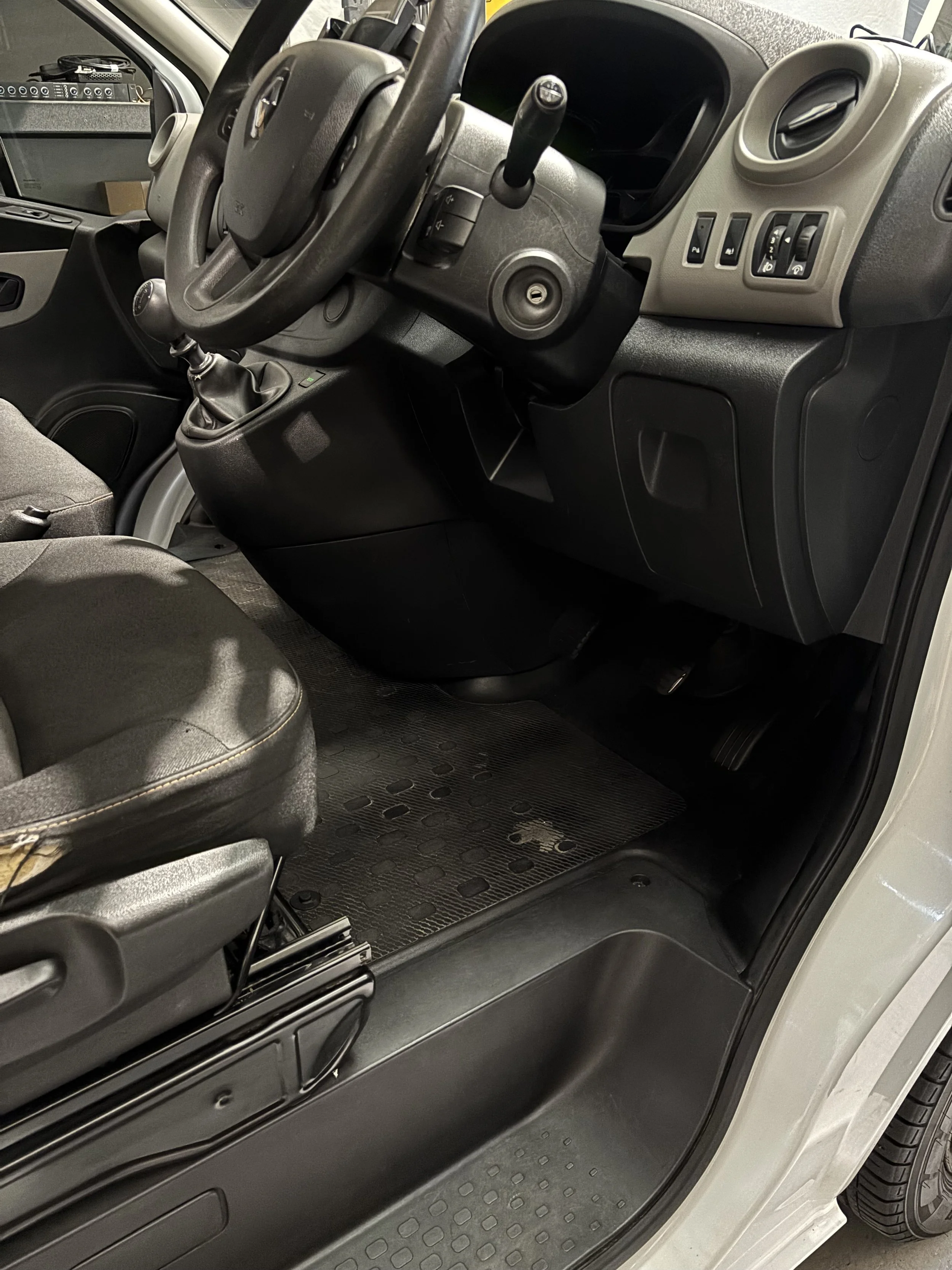 Interior view of a vehicle with a manual transmission, showing the driver's seat, steering wheel, dashboard, and part of the front passenger seat.
