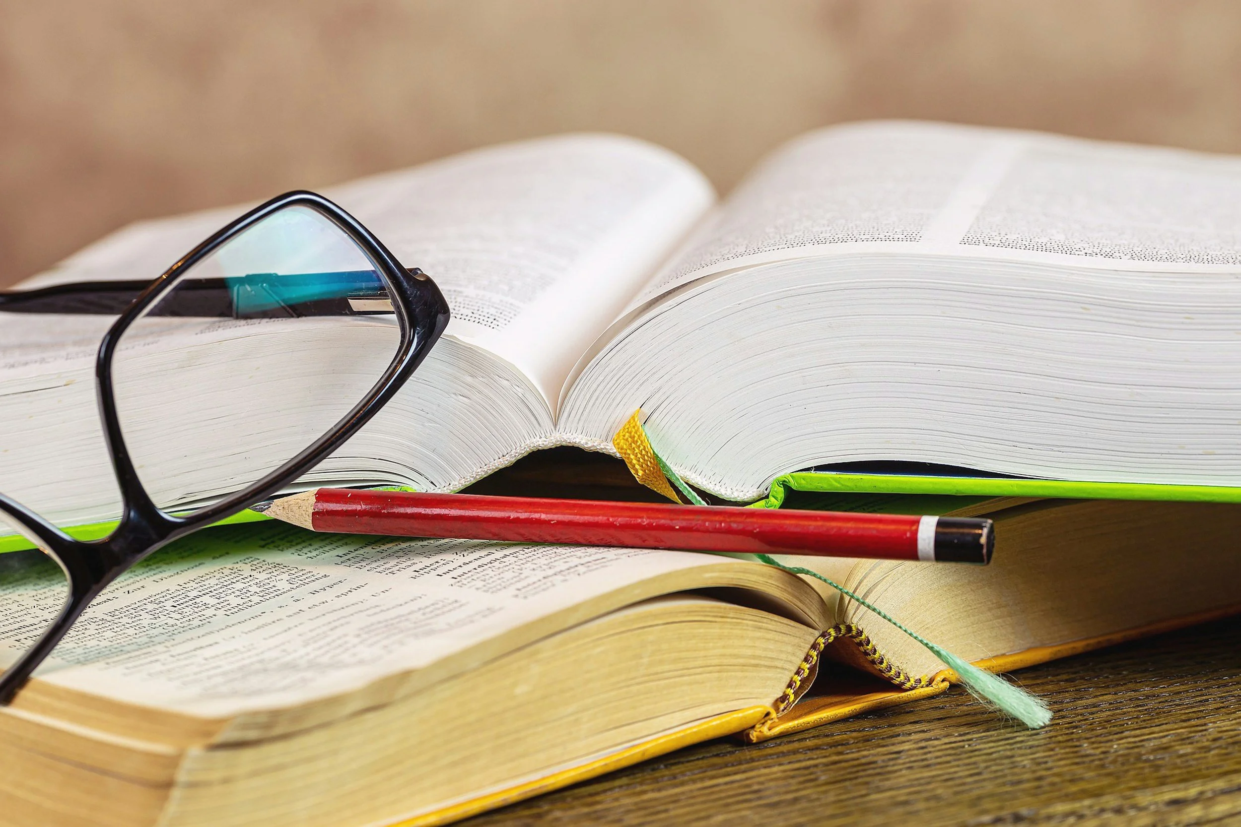 Open book with glasses and pencil on a desk — MrBrill evidence-based educational resources