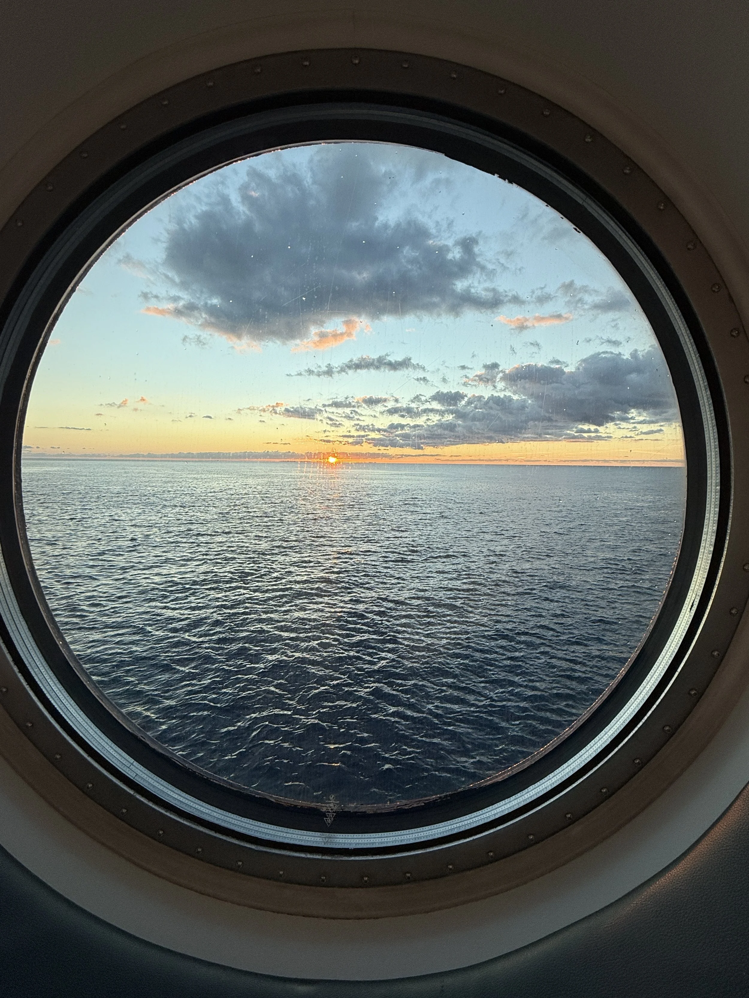 Sunset over the ocean viewed through an airplane window.
